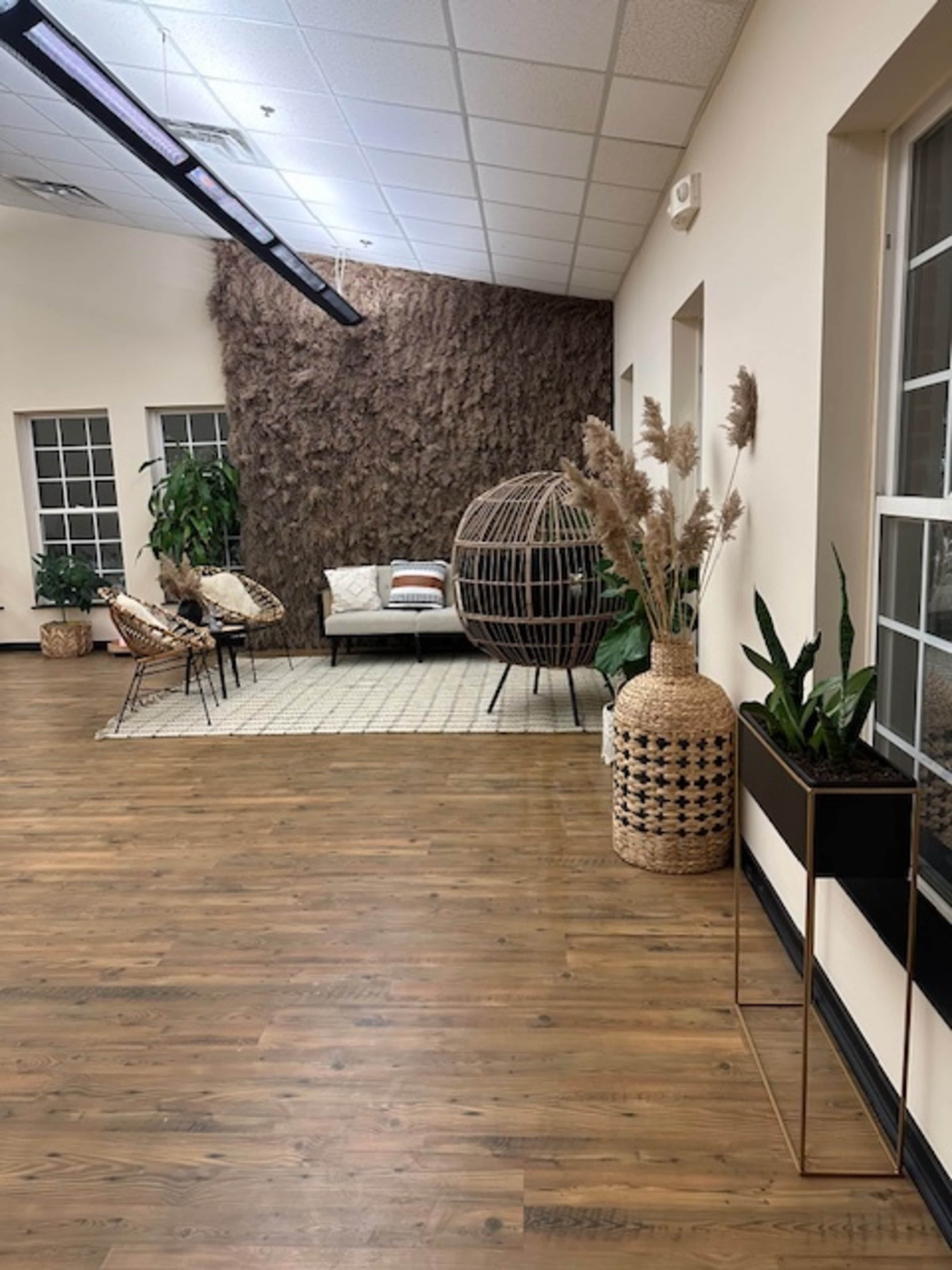 A modern interior space featuring a seating area with a couch, decorative plants, woven furniture, and a textured wall.