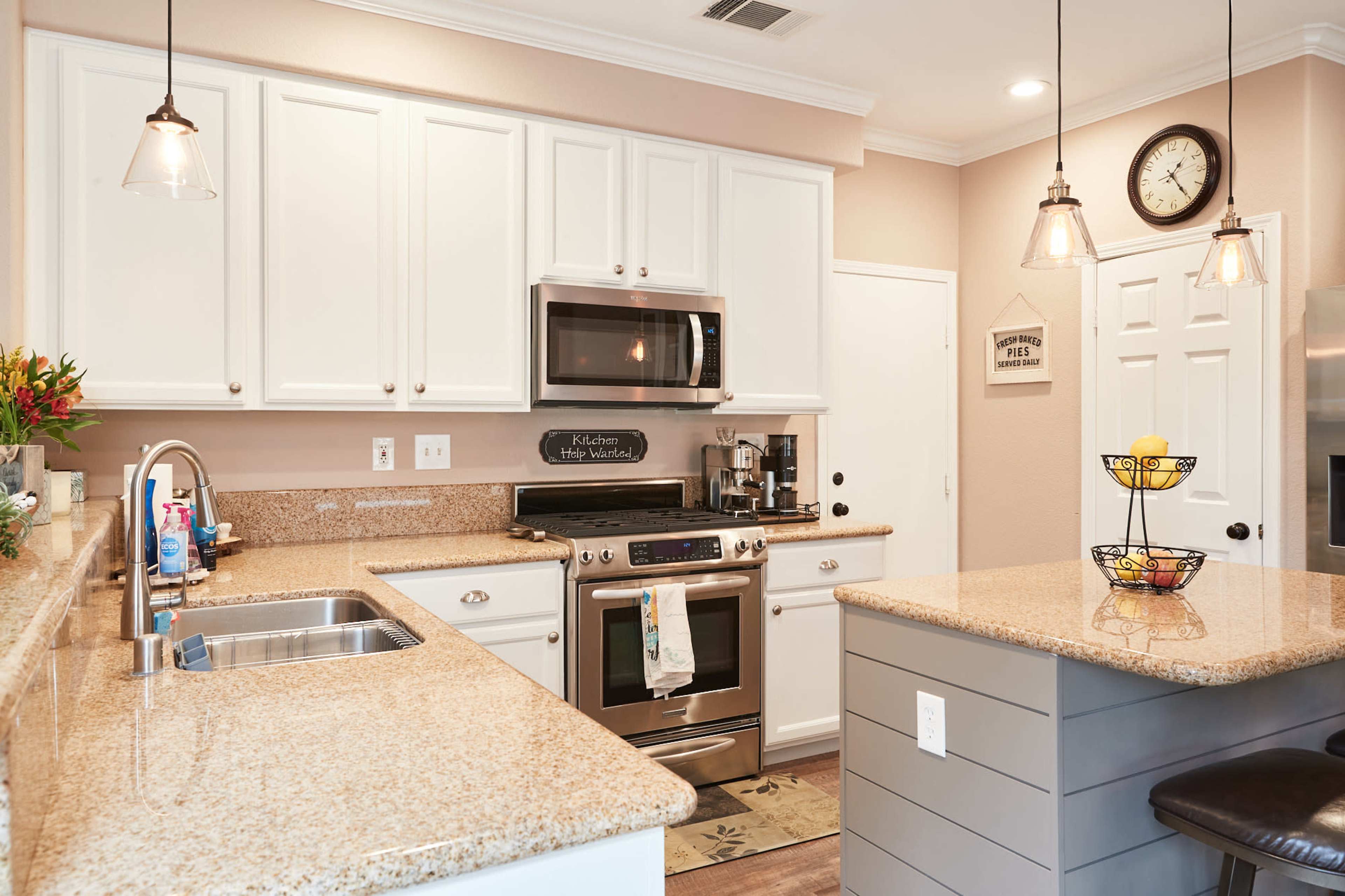 A modern kitchen with white cabinetry, stainless steel appliances, and a granite countertop island.