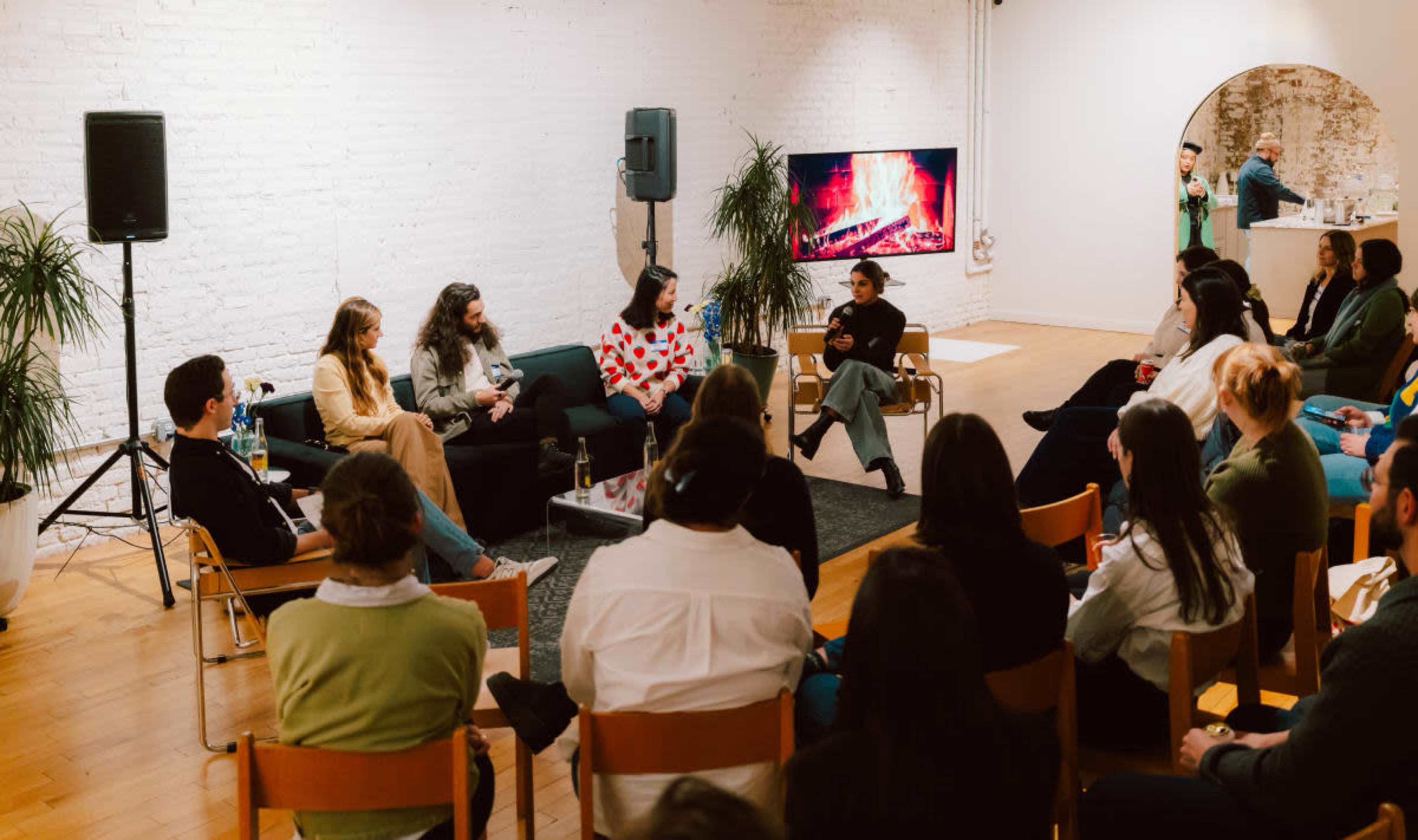 A panel discussion is taking place in a modern room, with a group of speakers seated in front of an audience.