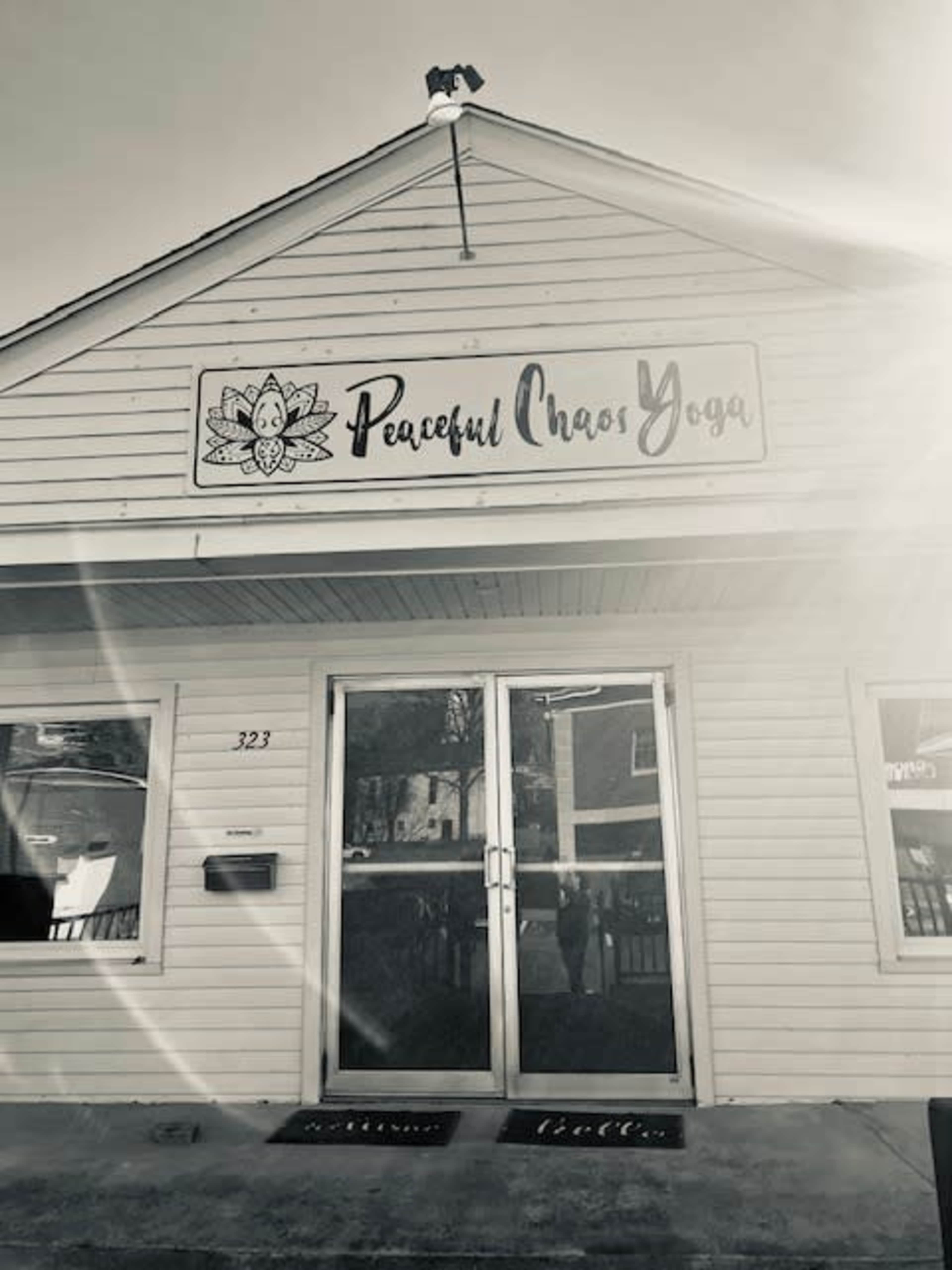 The exterior of a yoga studio named "Peaceful Chaos Yoga" with a sign above the entrance and a clear address visible on the building.