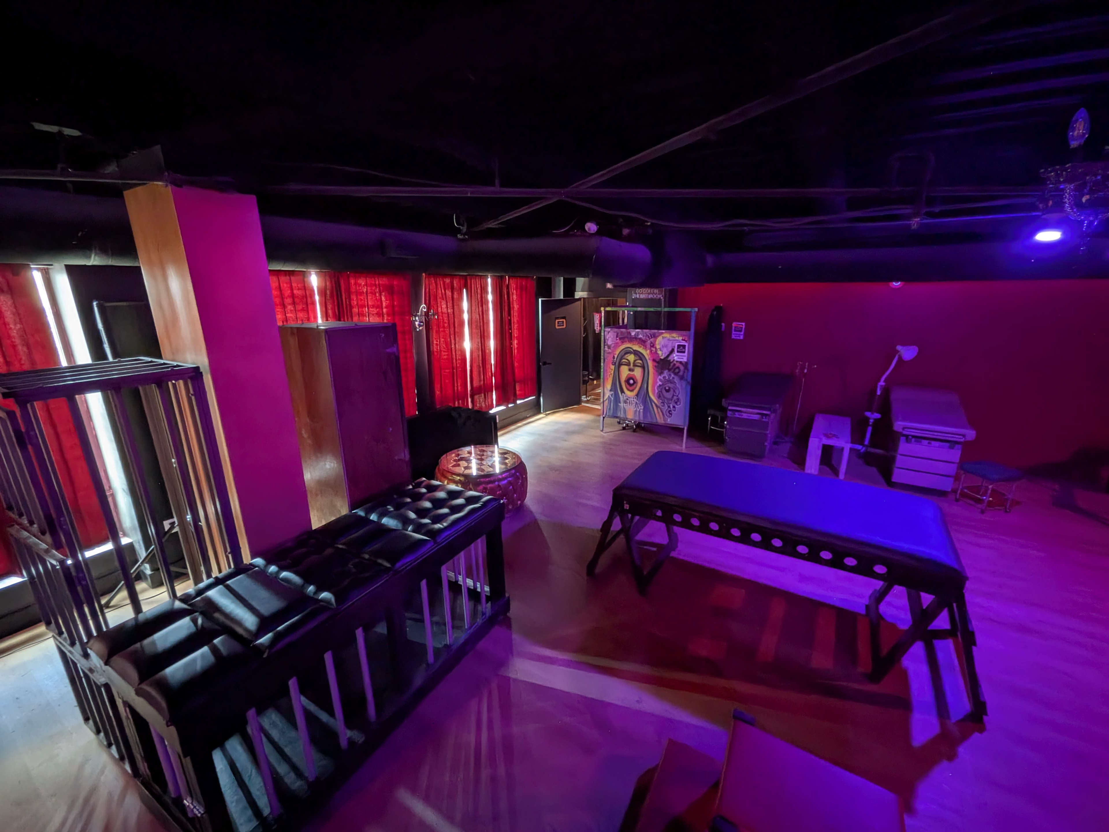 The image shows an interior space with various pieces of equipment including tables, a massaging station, and colorful lighting.