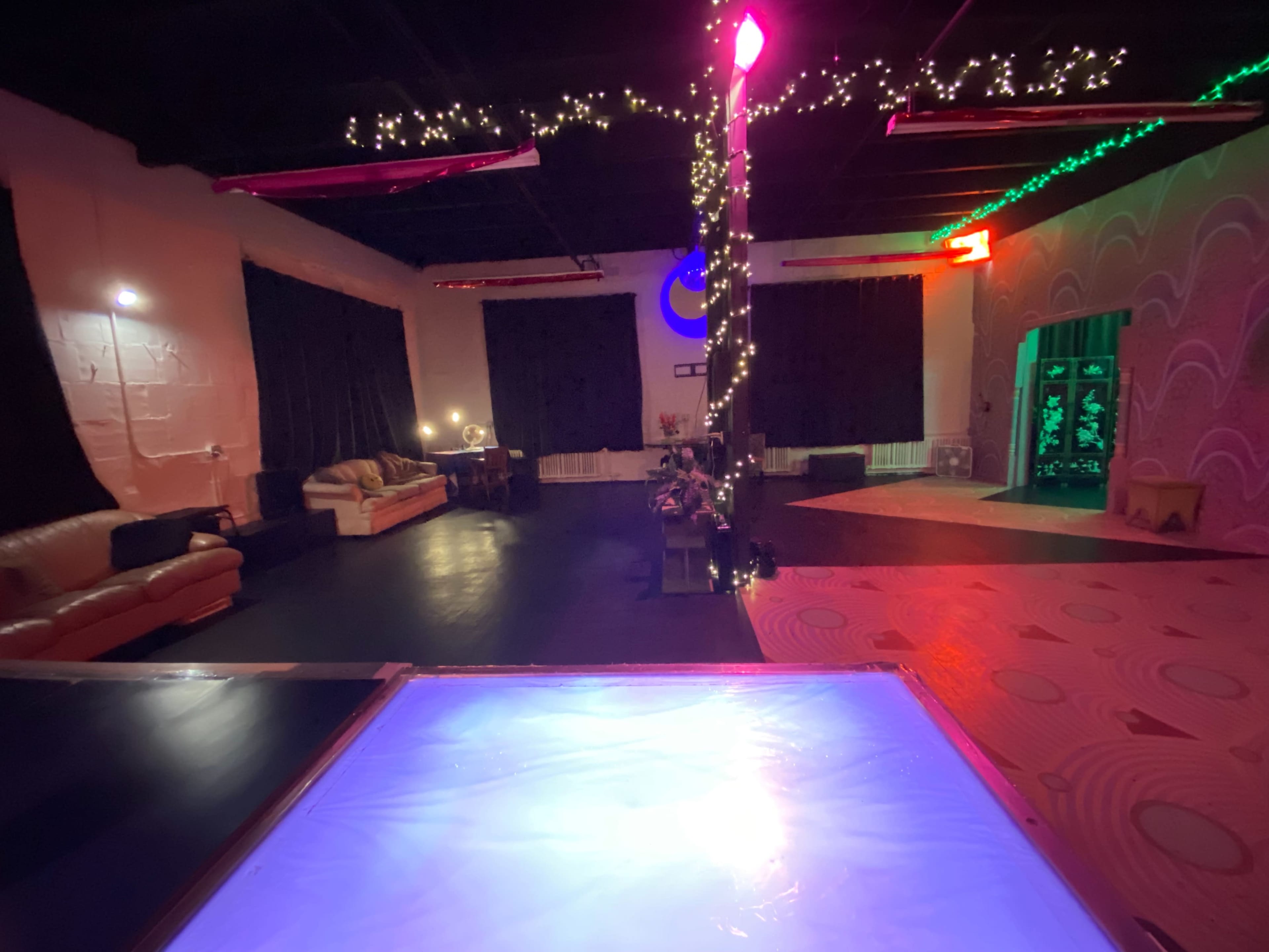 A spacious room with a dance floor, couches, and decorations including string lights.