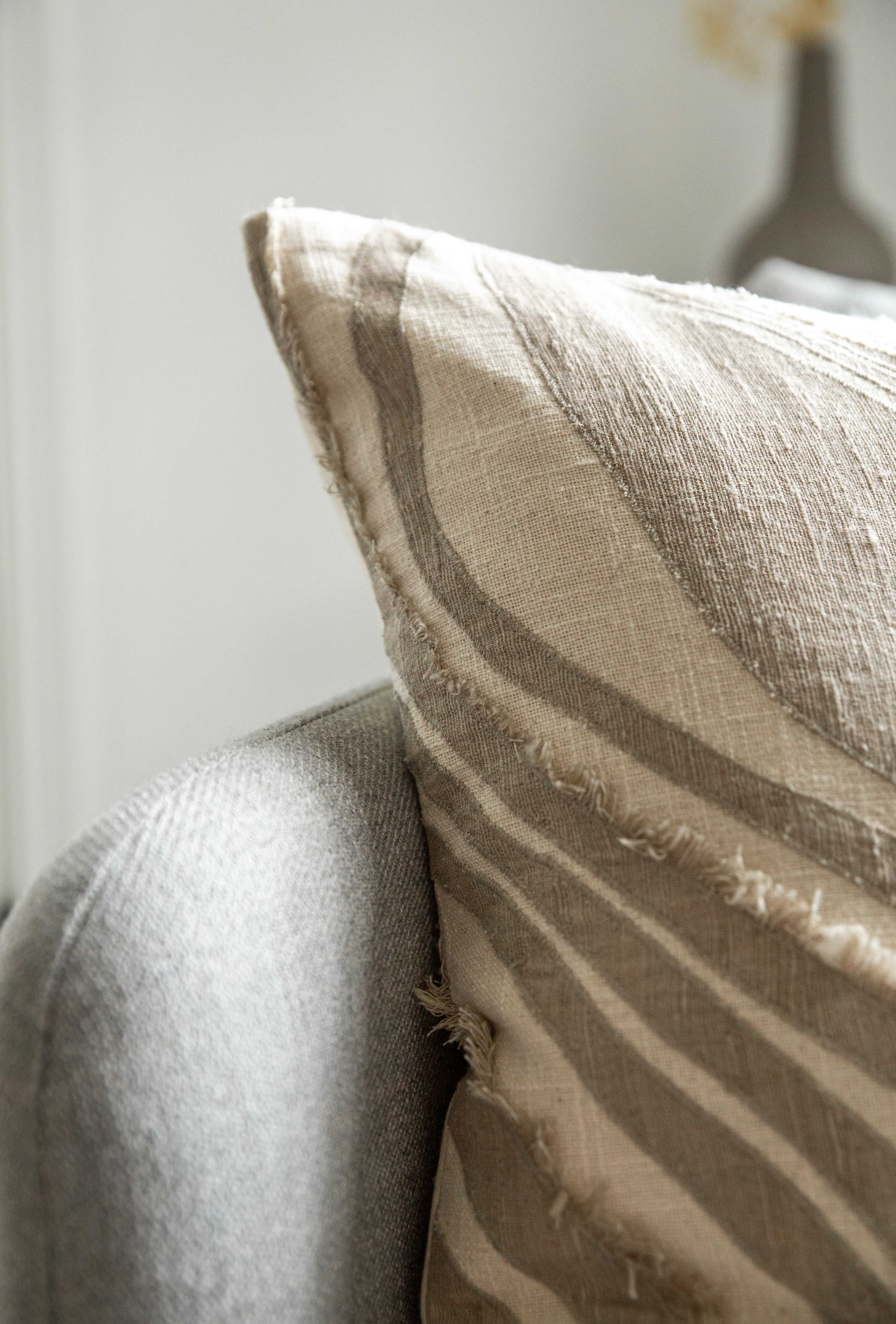 A close-up view of a textured cushion resting against a gray upholstered chair.