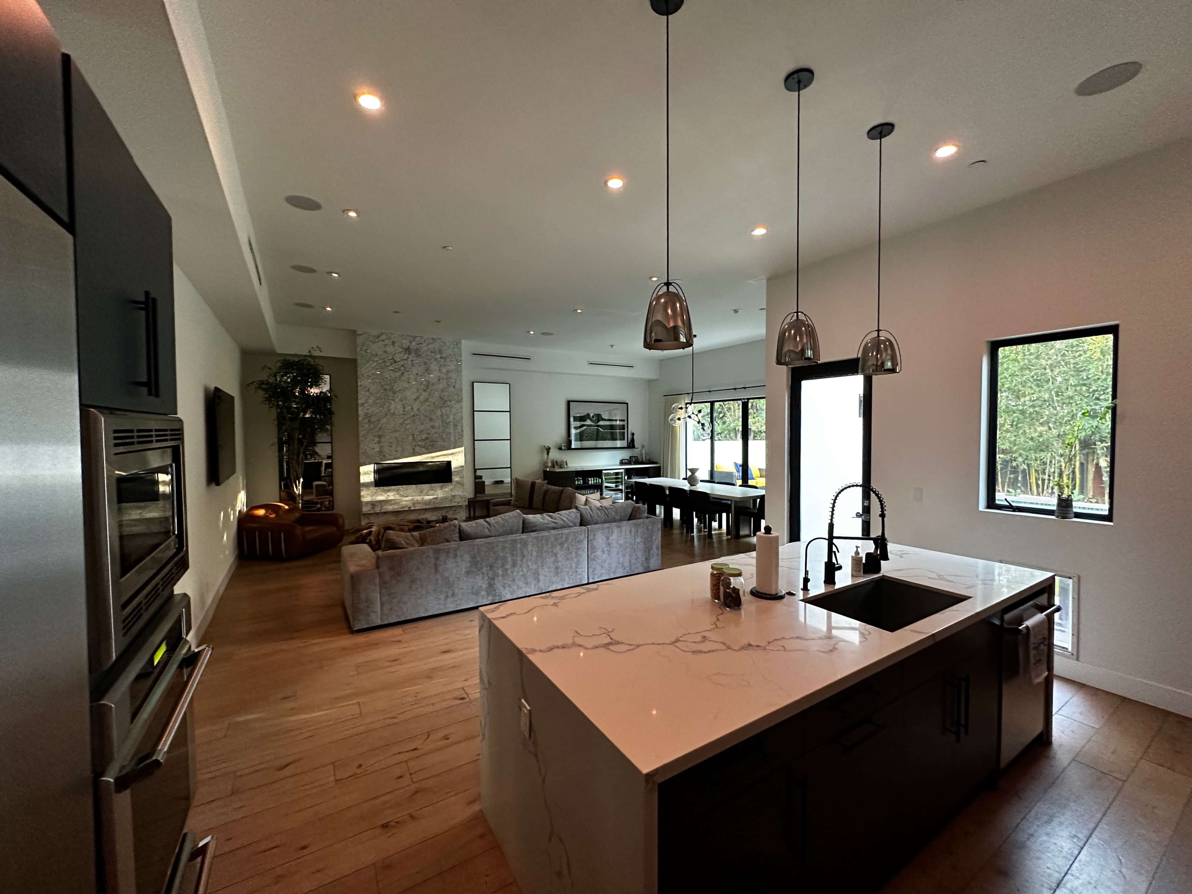 A modern kitchen with a large island, sleek appliances, and an open layout leading to a living area and dining space.