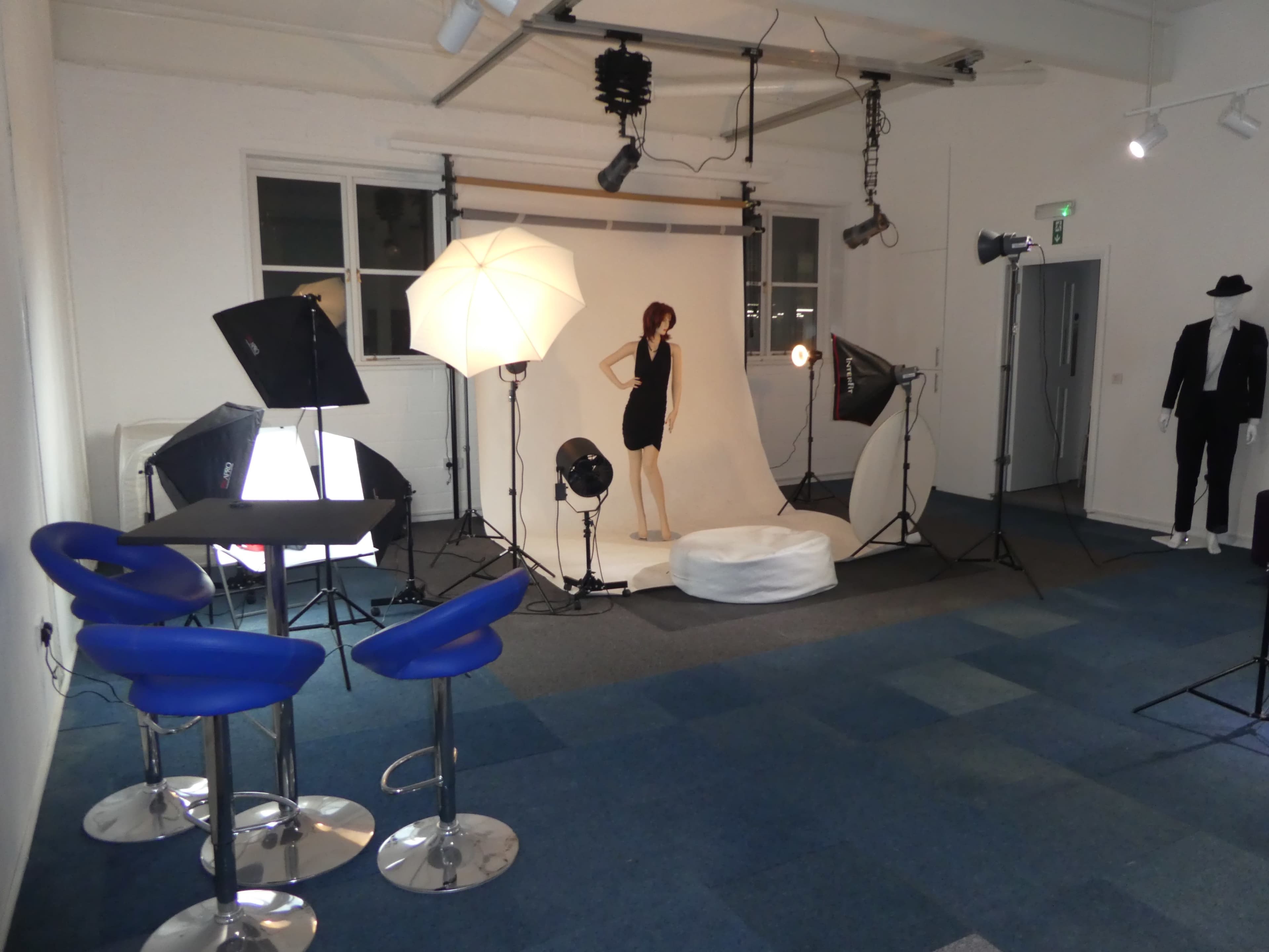 A photography studio is set up with lighting equipment and a mannequin on a white backdrop.