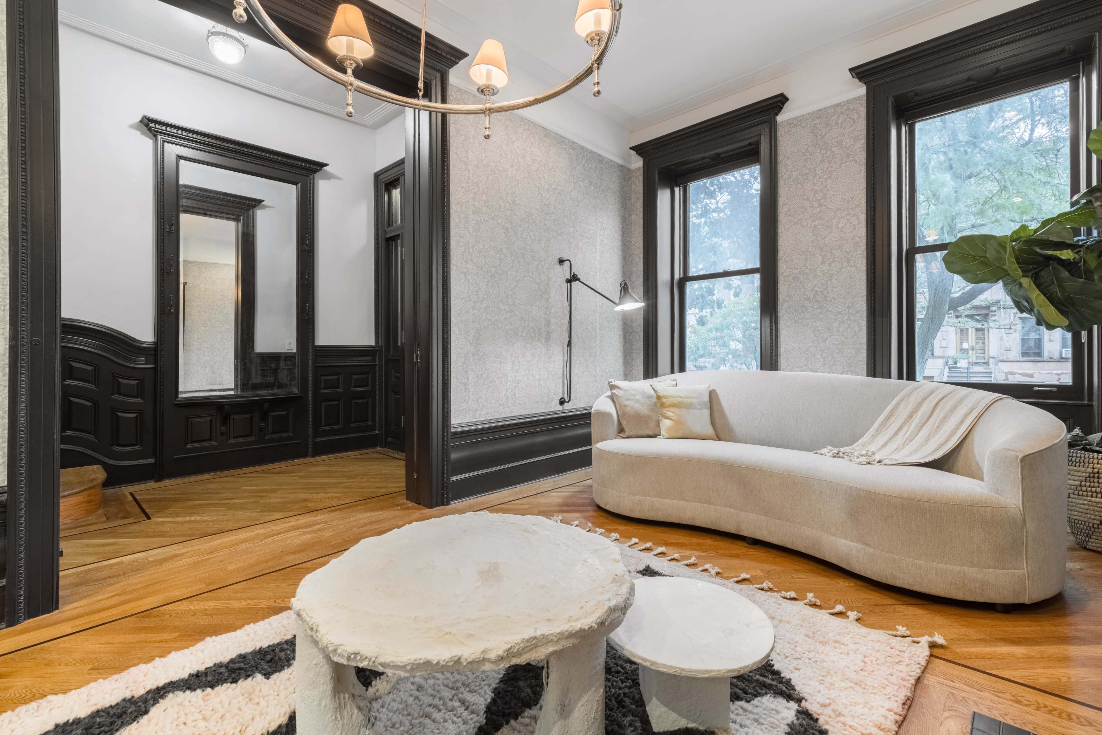 A well-lit living room with a curved beige sofa, a patterned area rug, and a small round coffee table.