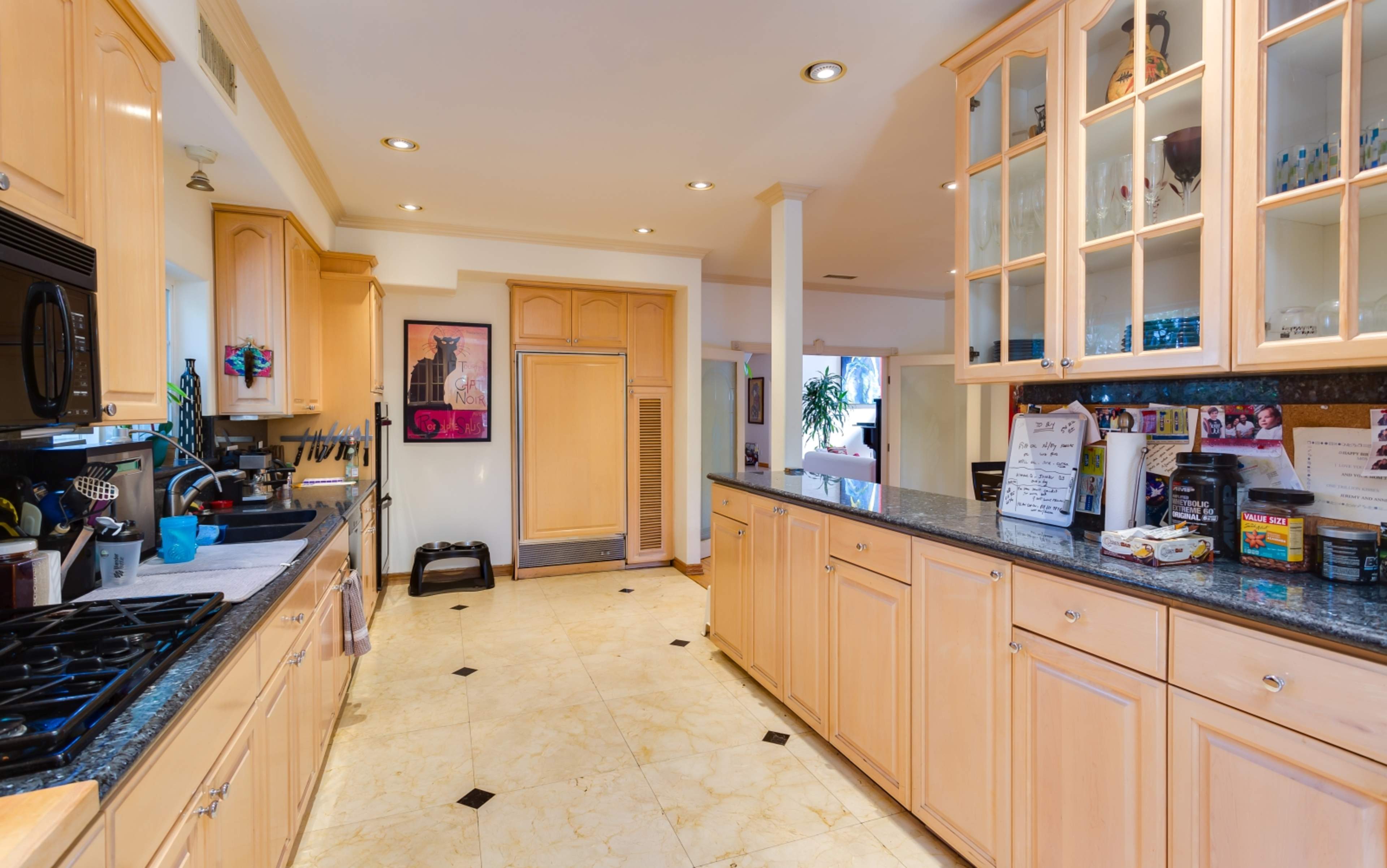 A modern kitchen with wooden cabinets, a granite countertop, and various kitchen appliances along one side.