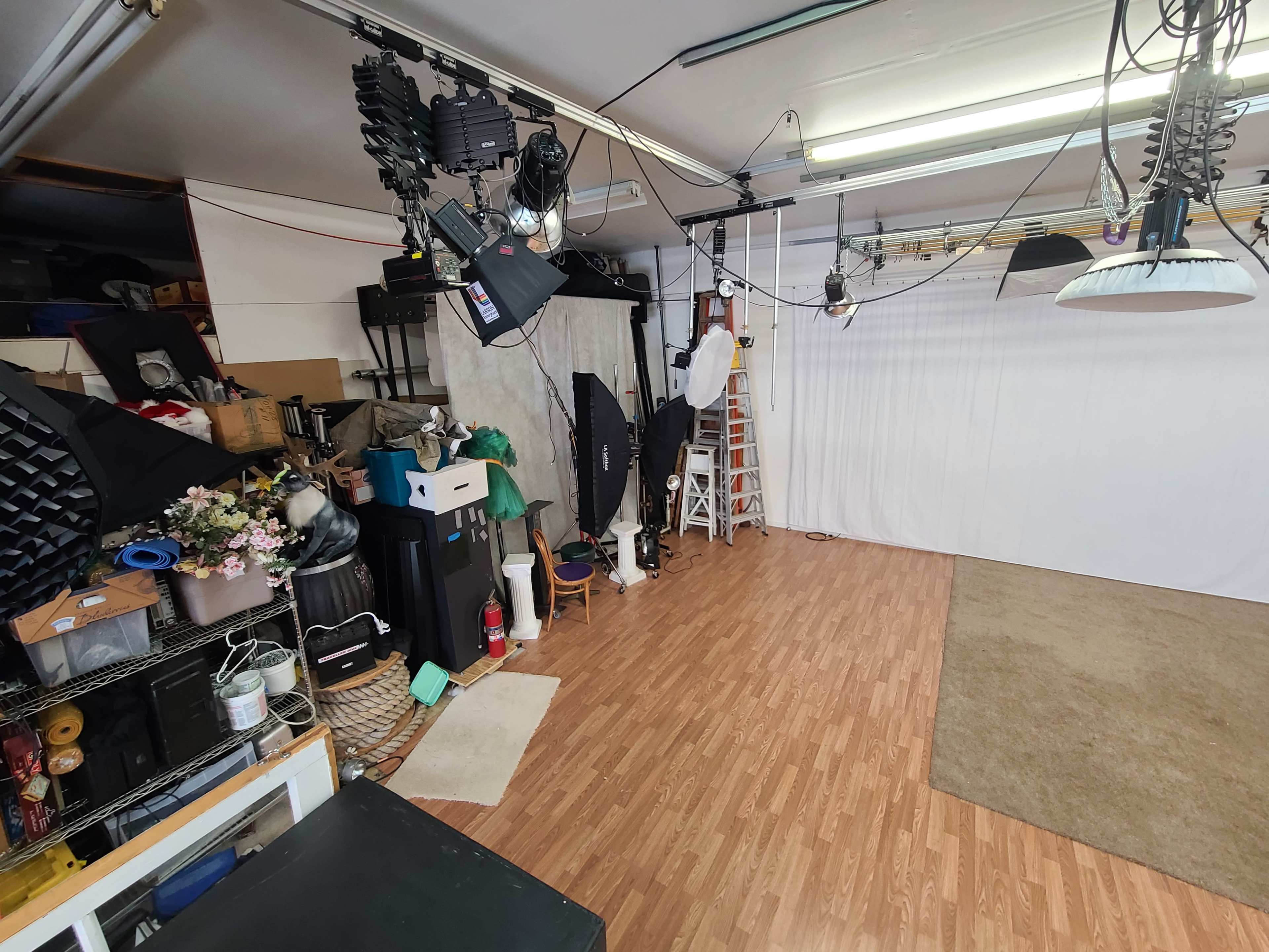 A photography studio with various lighting equipment, backdrops, and props organized on shelves and the floor.