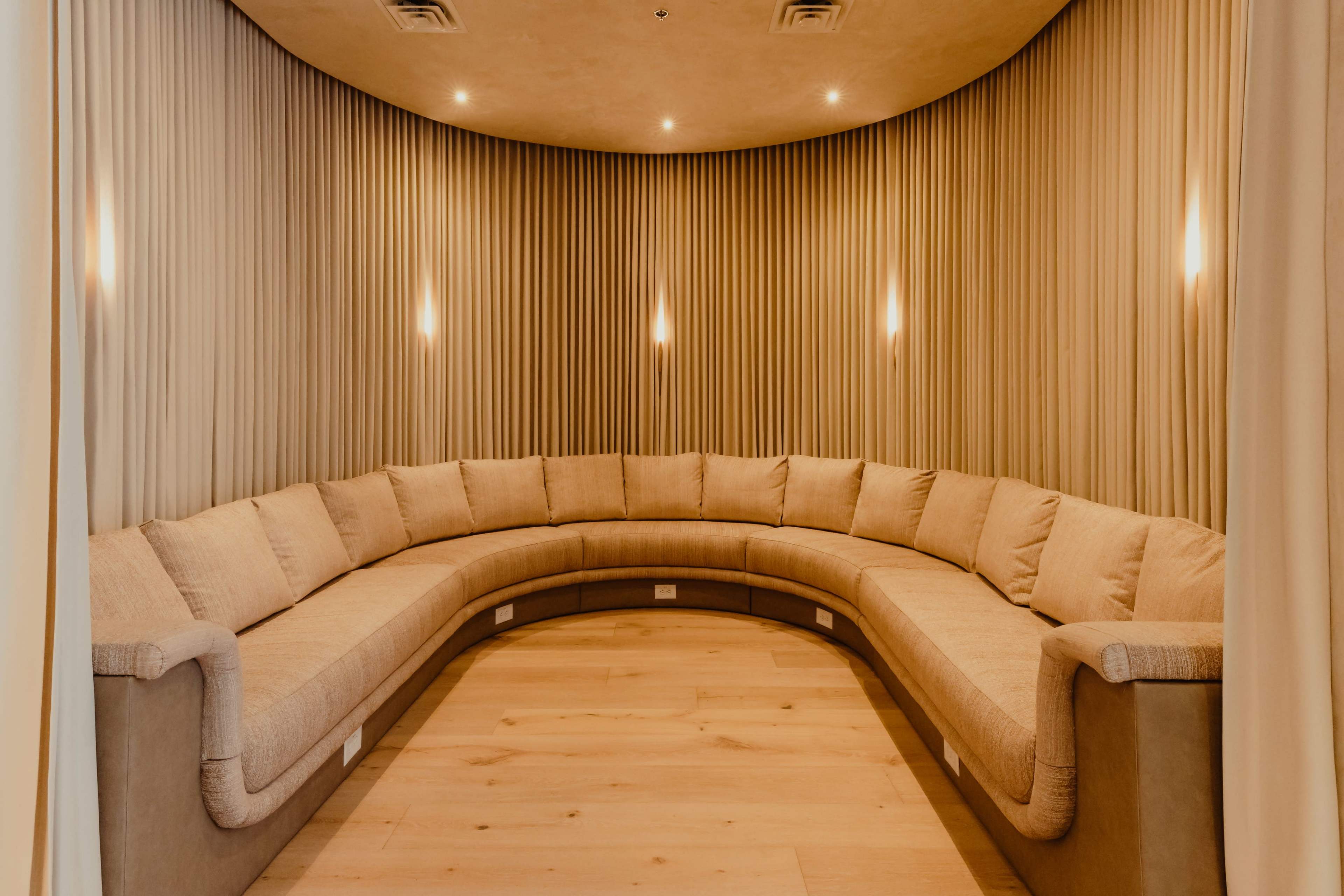 The image features a curved, upholstered seating area with soft lighting in a cozy, enclosed space.