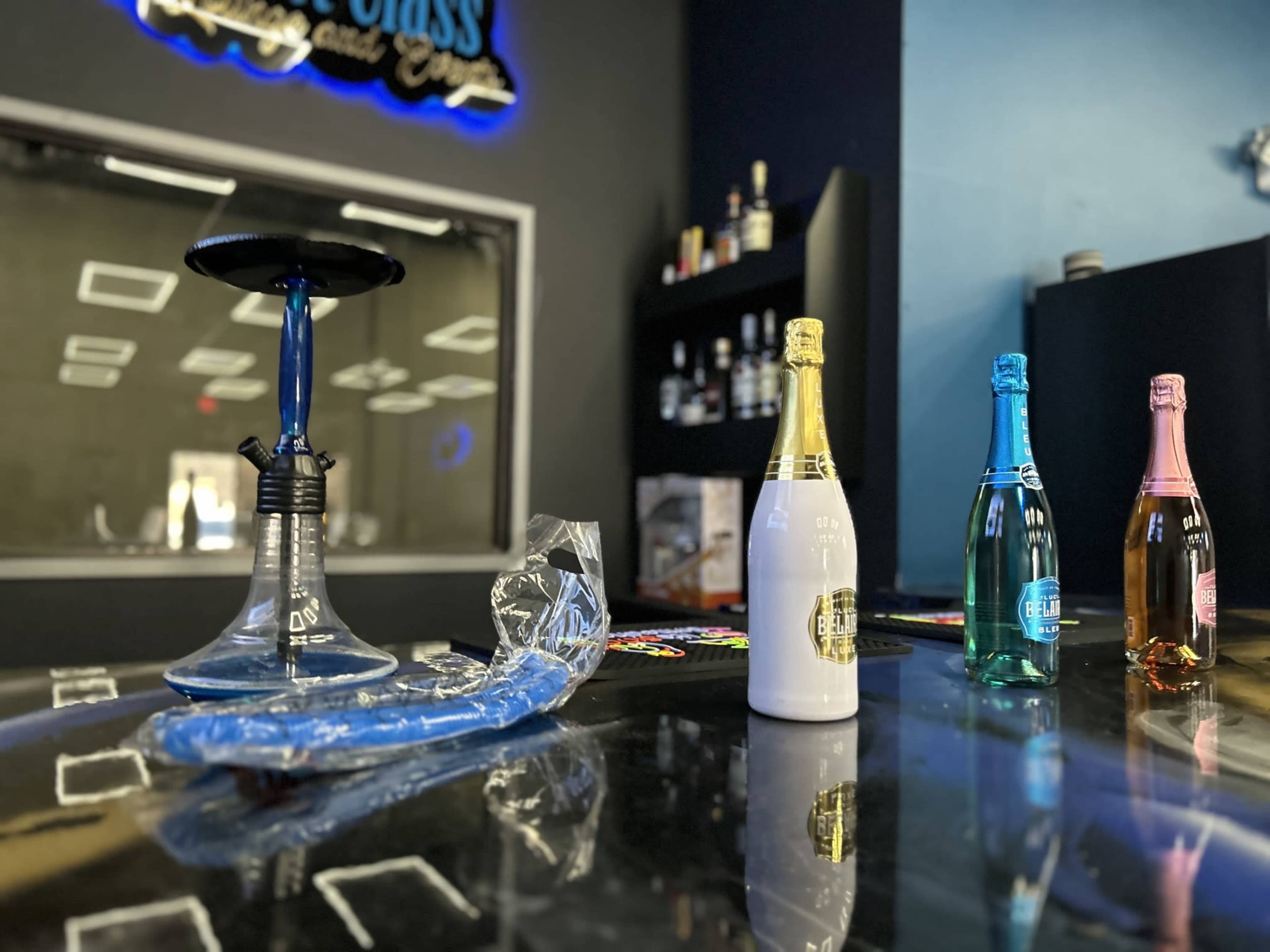 A hookah setup is placed on a counter beside four colorful bottles of flavored beverages.