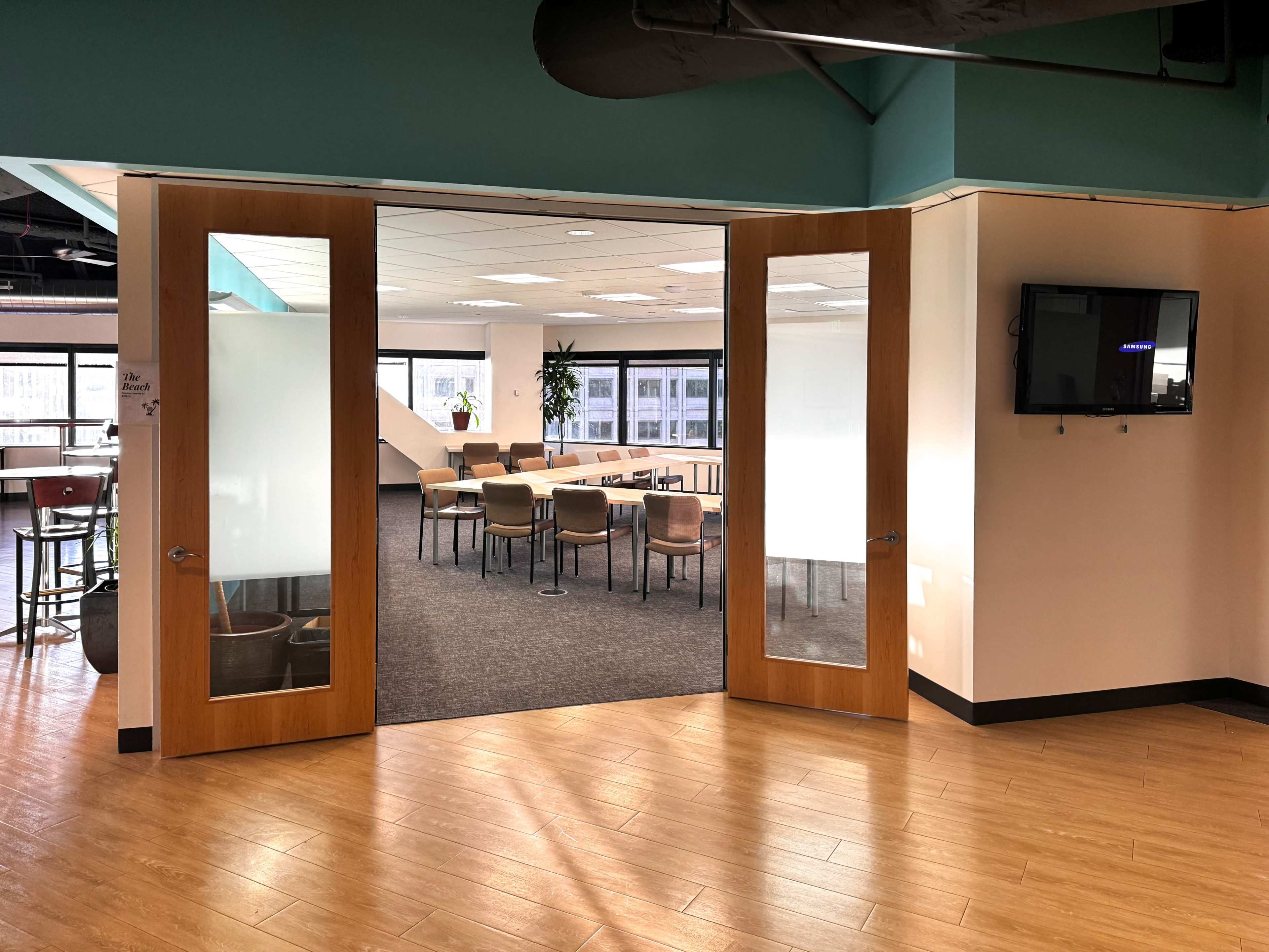 A doorway leading into a modern conference room with a large table and several chairs arranged around it.