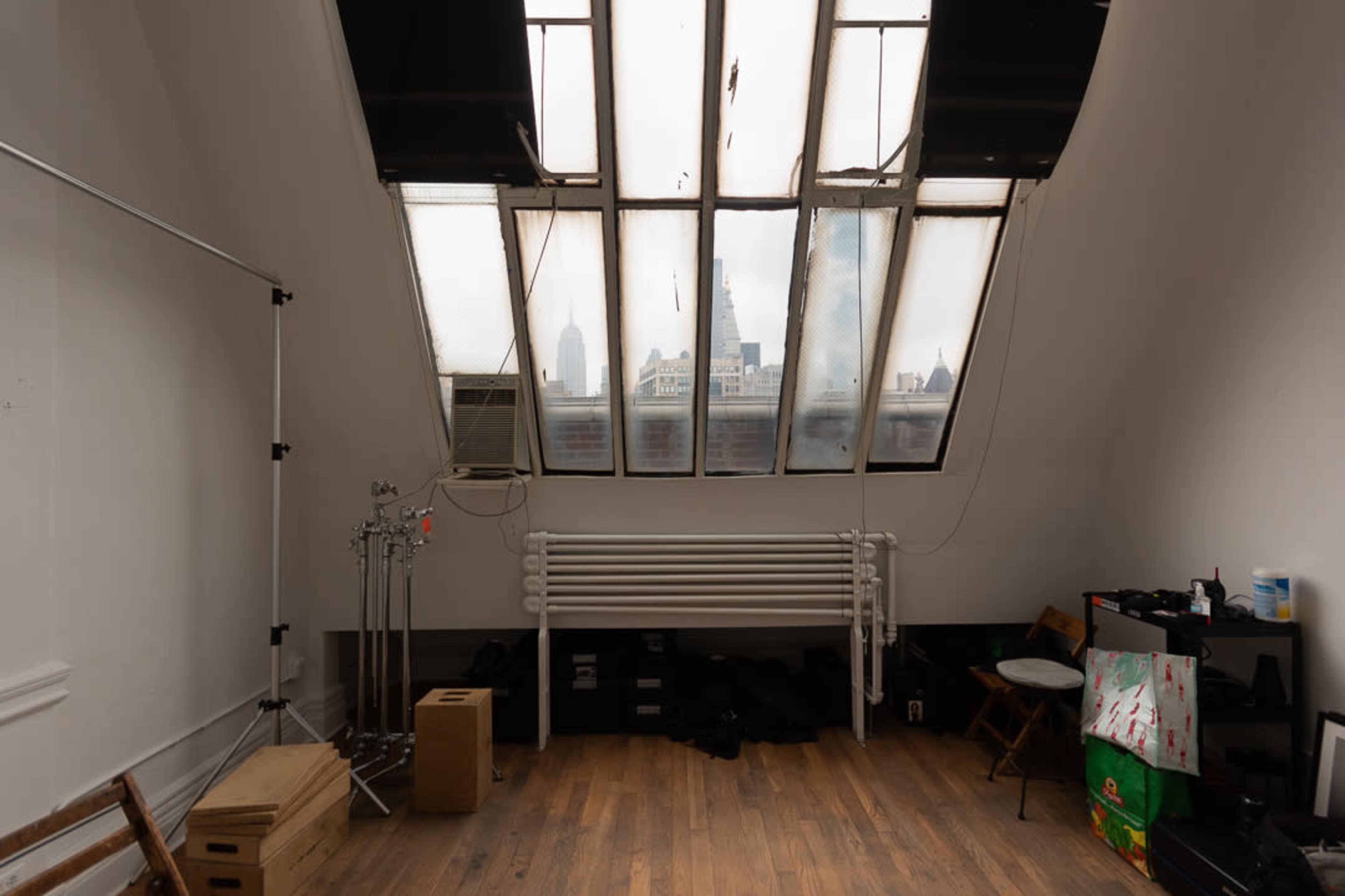 An industrial-style room with large, dirty windows overhead, revealing a view of tall buildings outside.