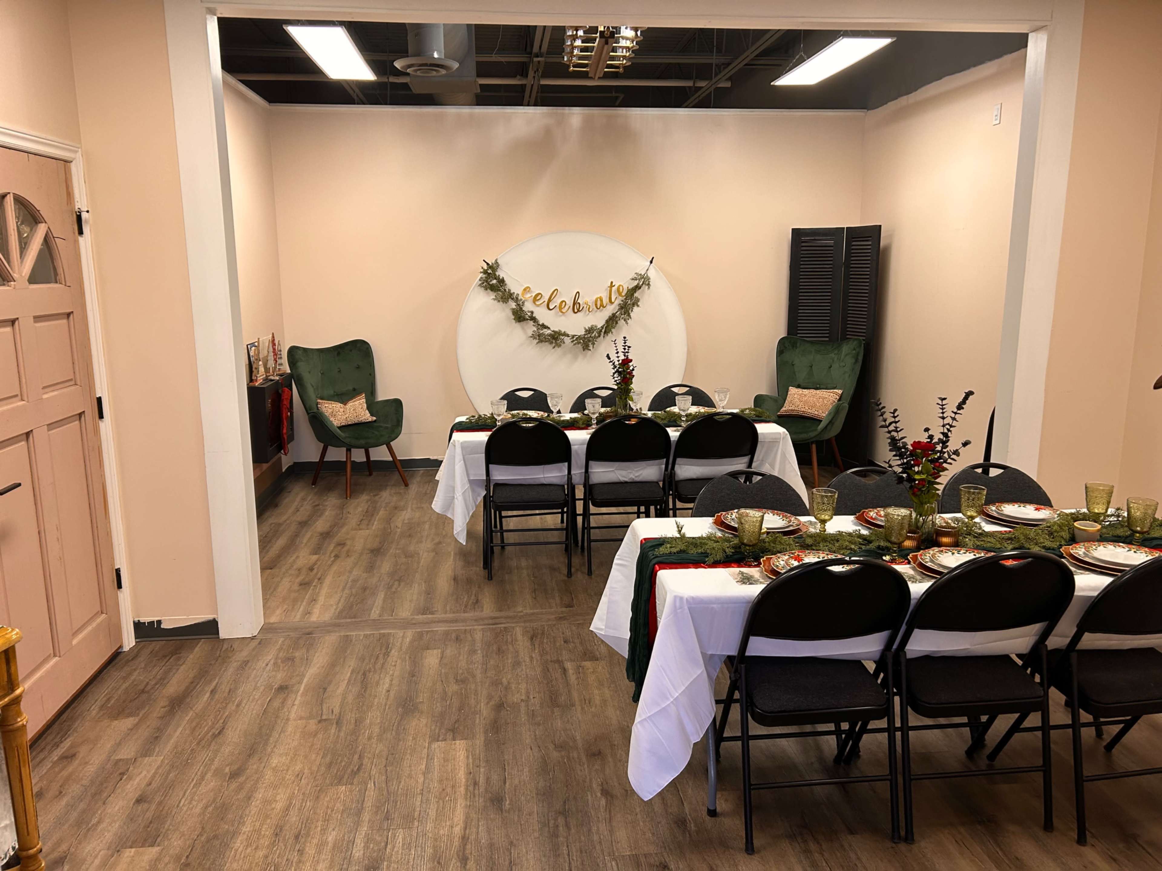 A decorated dining area features two tables set with green dishware and a "Celebrate" banner on the wall, along with two green chairs in the corners.