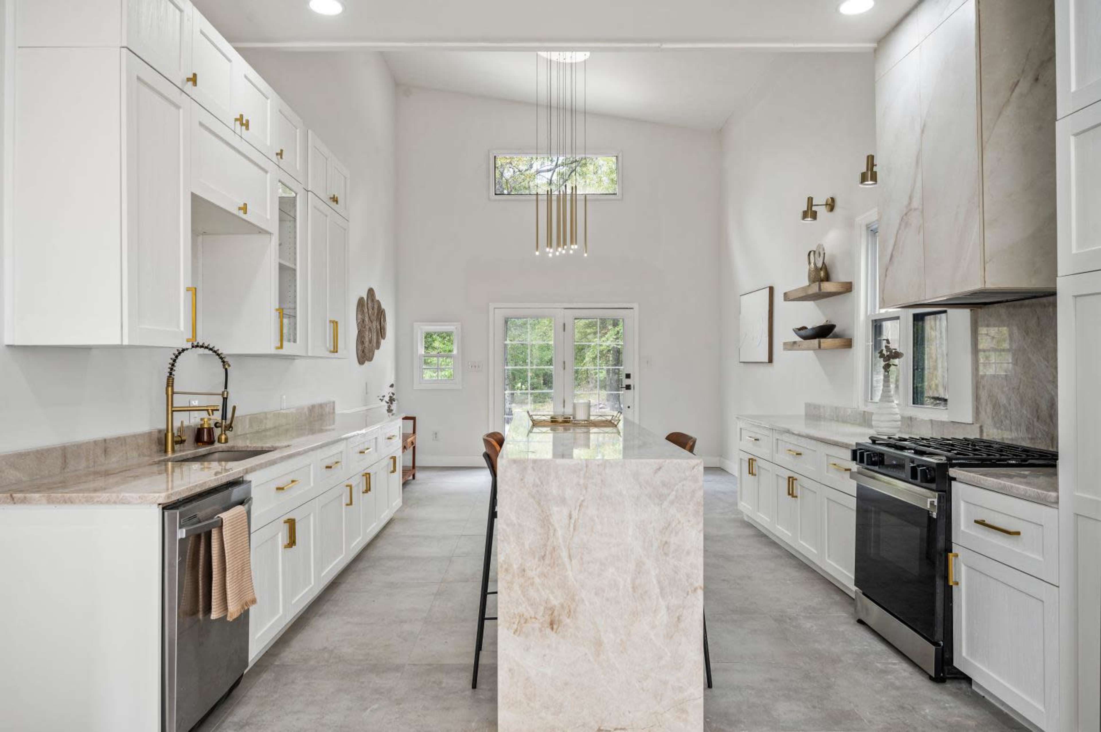 The image shows a modern kitchen with white cabinetry, marble countertops, and a large central island.