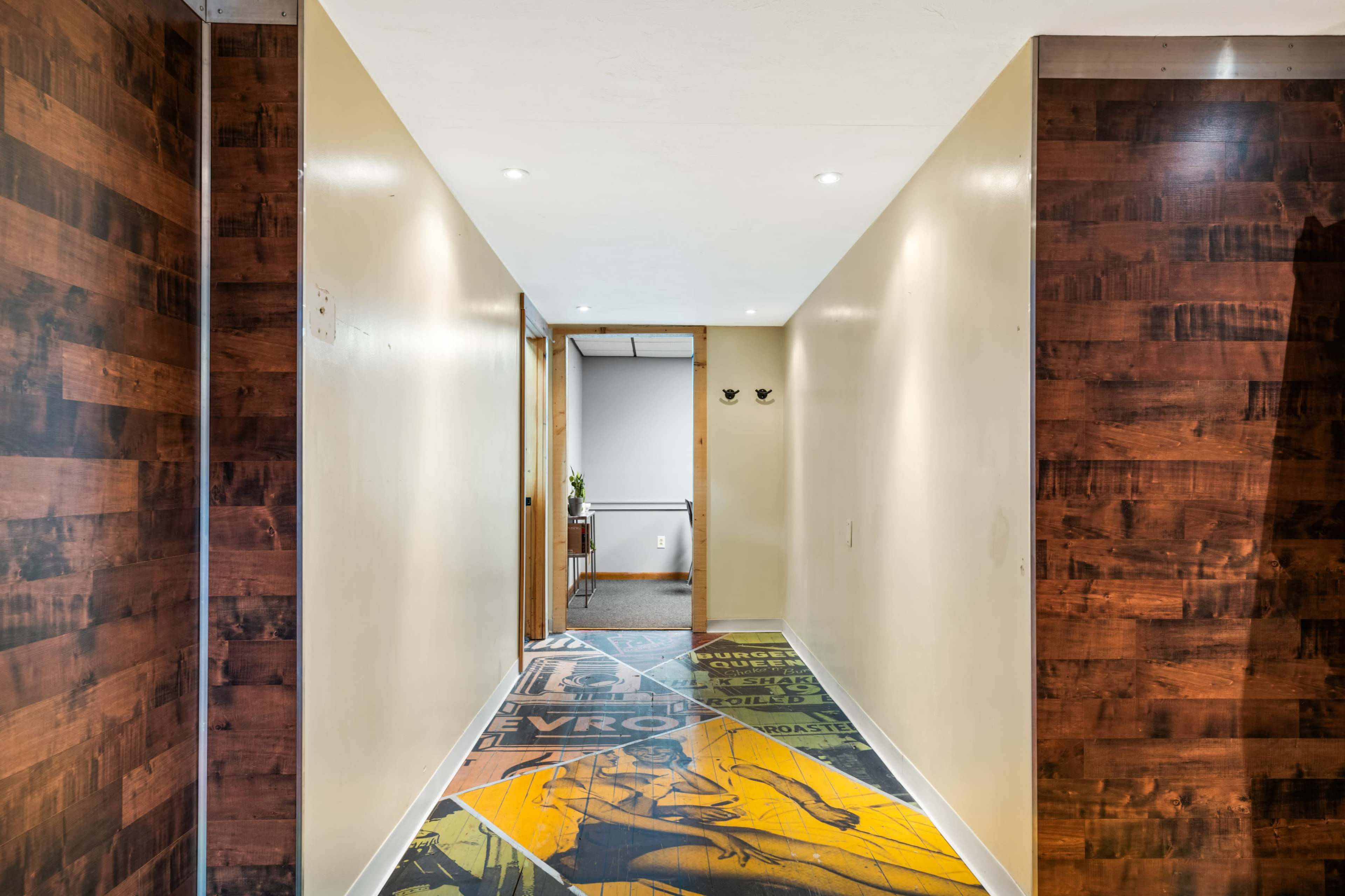 A long hallway with patterned flooring, leading to an open door at the end.