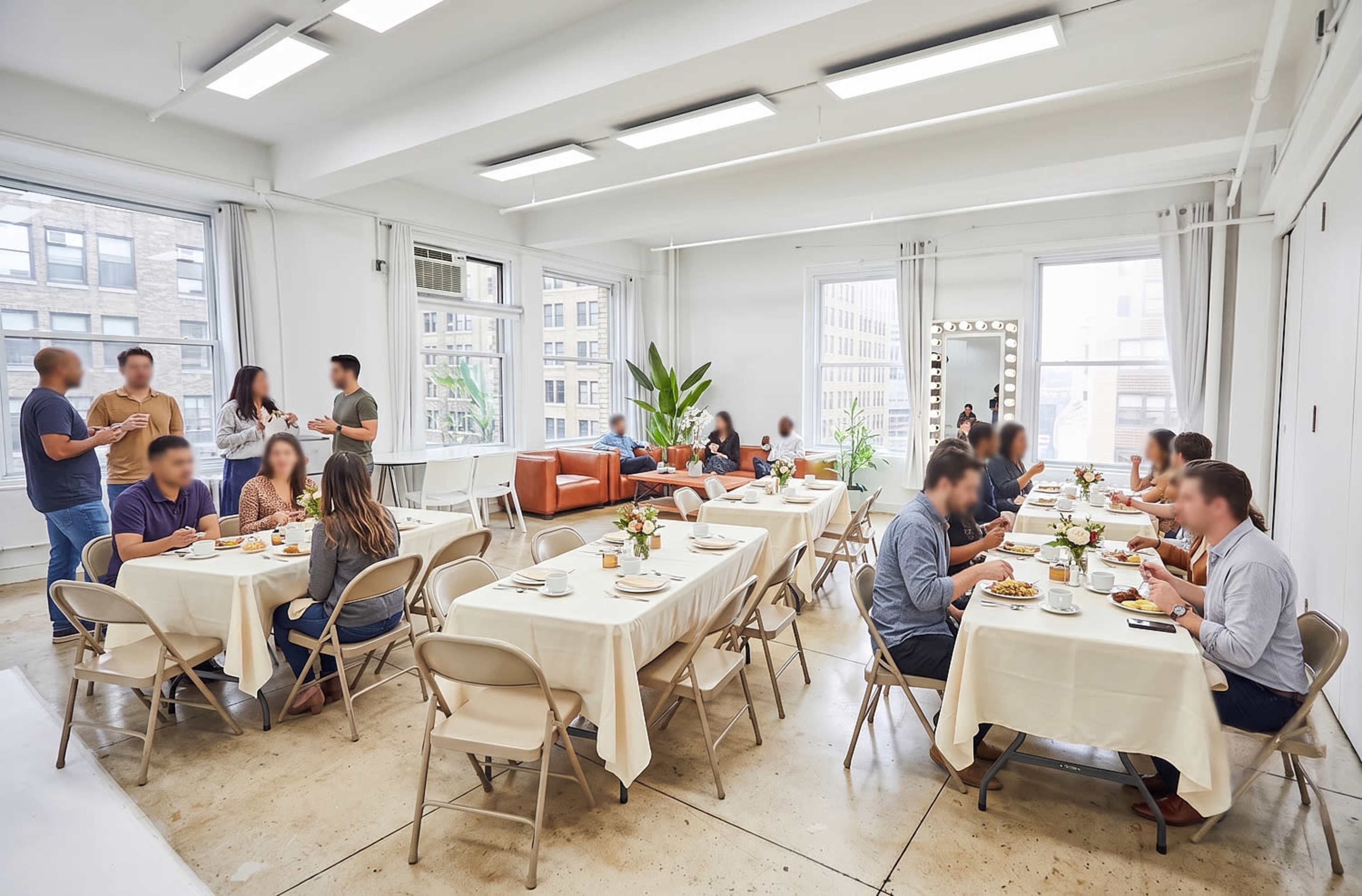 A group of people are dining at tables in a bright, modern room with large windows and plants.