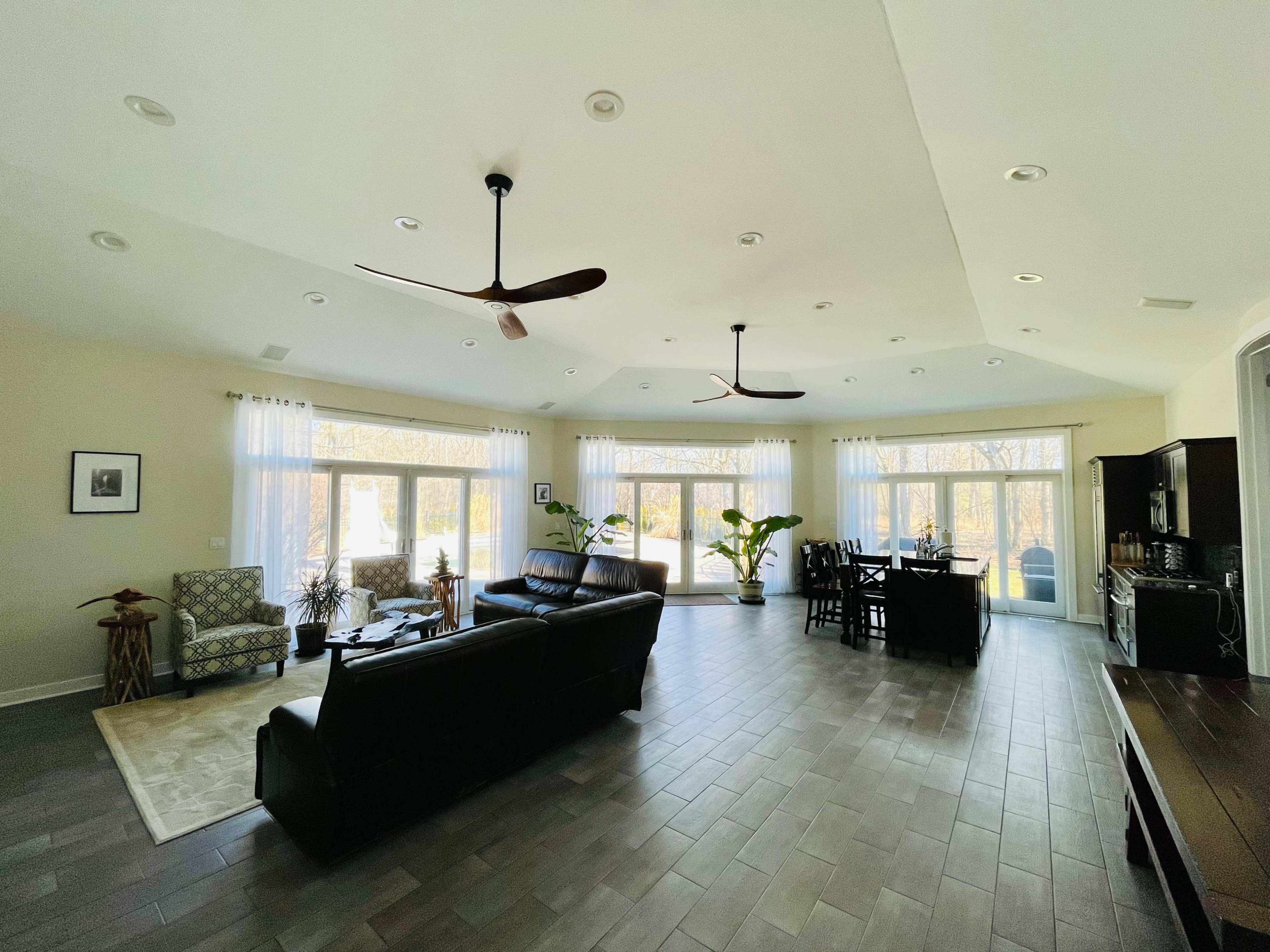 A spacious interior living area with large windows, modern furniture, and a dining set.