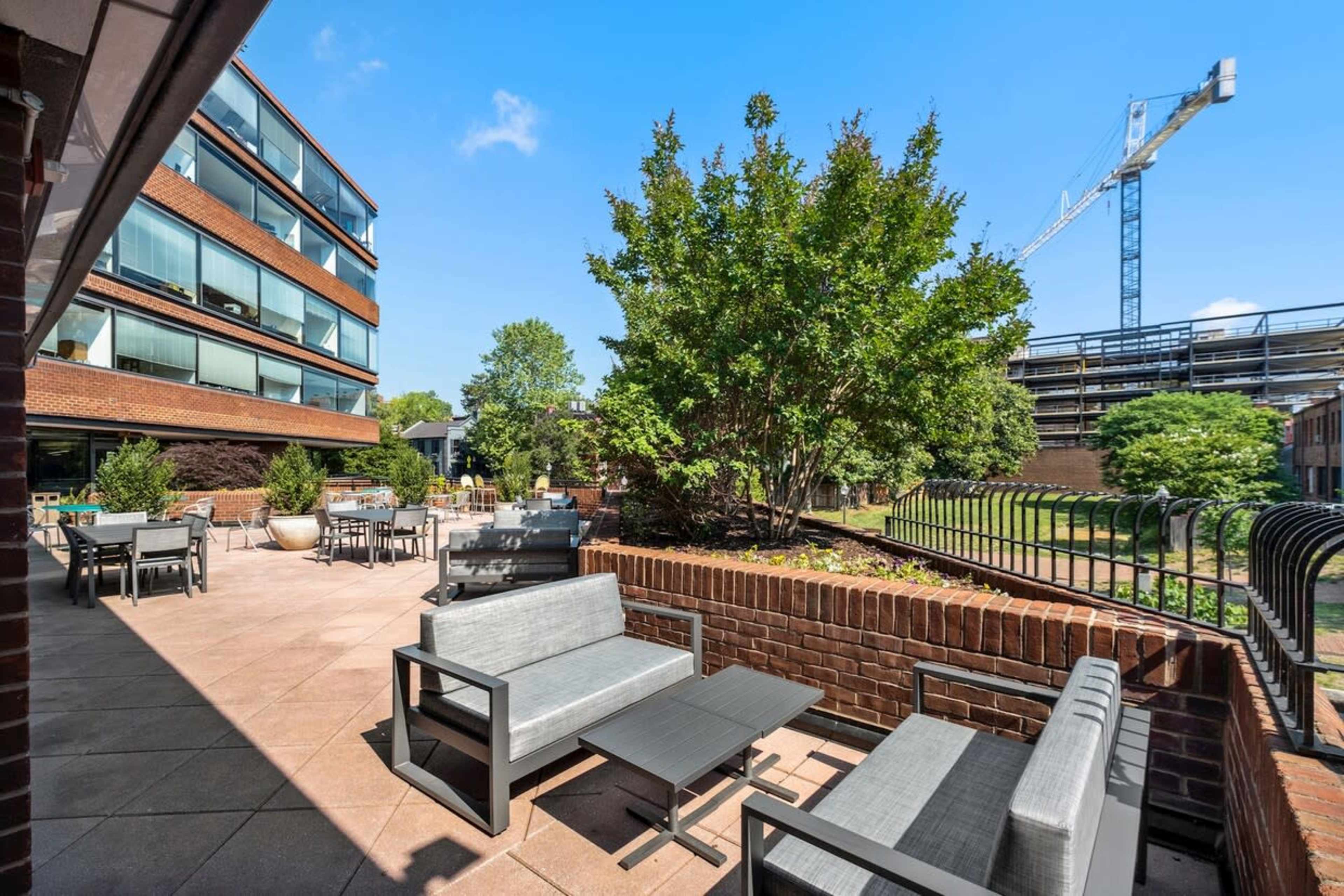 A patio area with modern furniture overlooks greenery and a construction site in the background.