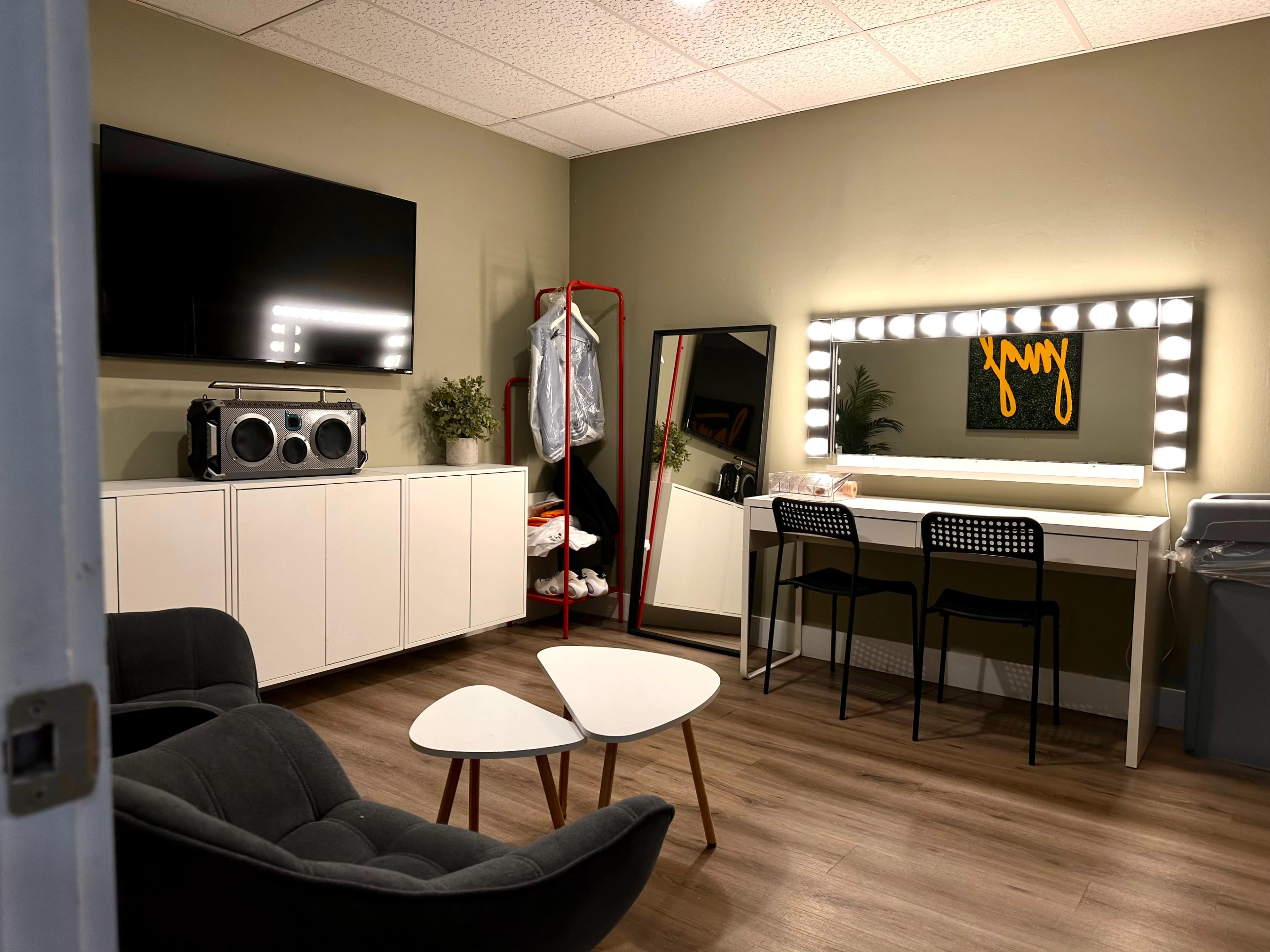 A modern room with a large mirror and vanity lights, a sofa, a small coffee table, and a television mounted on the wall.