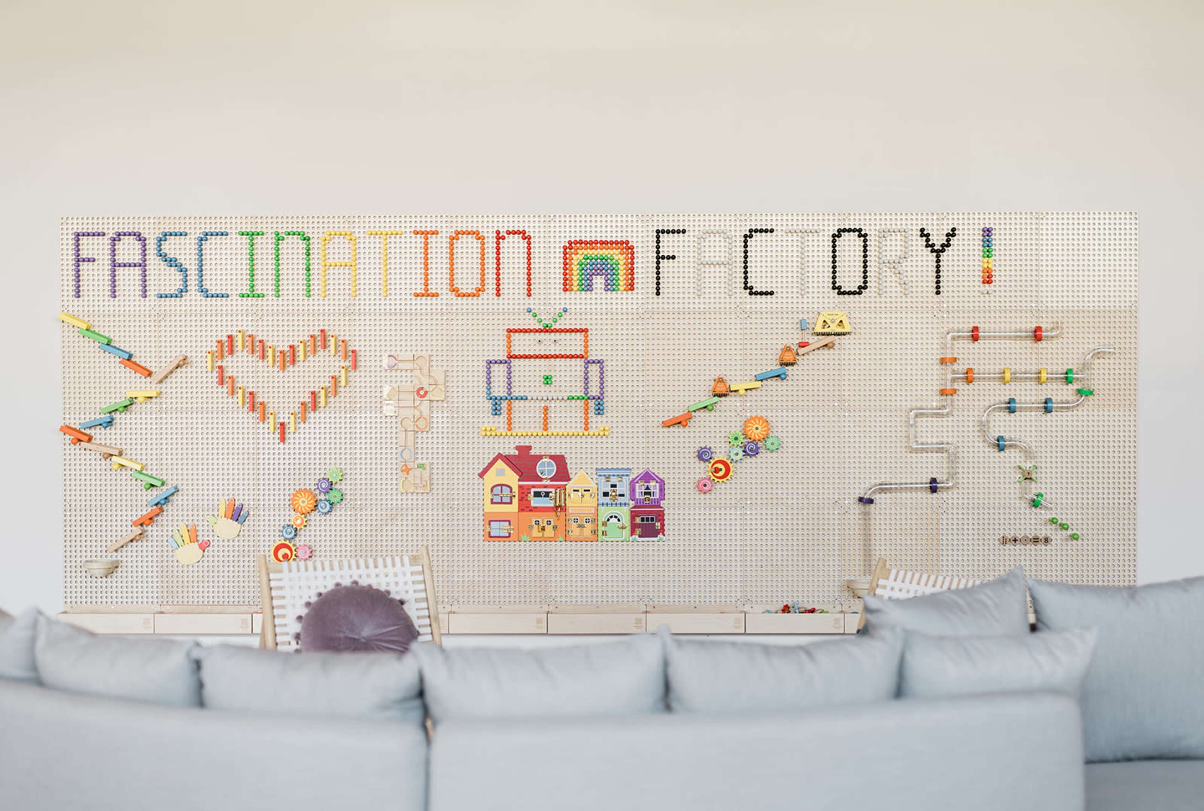 A colorful wall display features various toys and decorations arranged to form the words "FASCINATION" and "FCOY," alongside shapes like hearts and a robot.