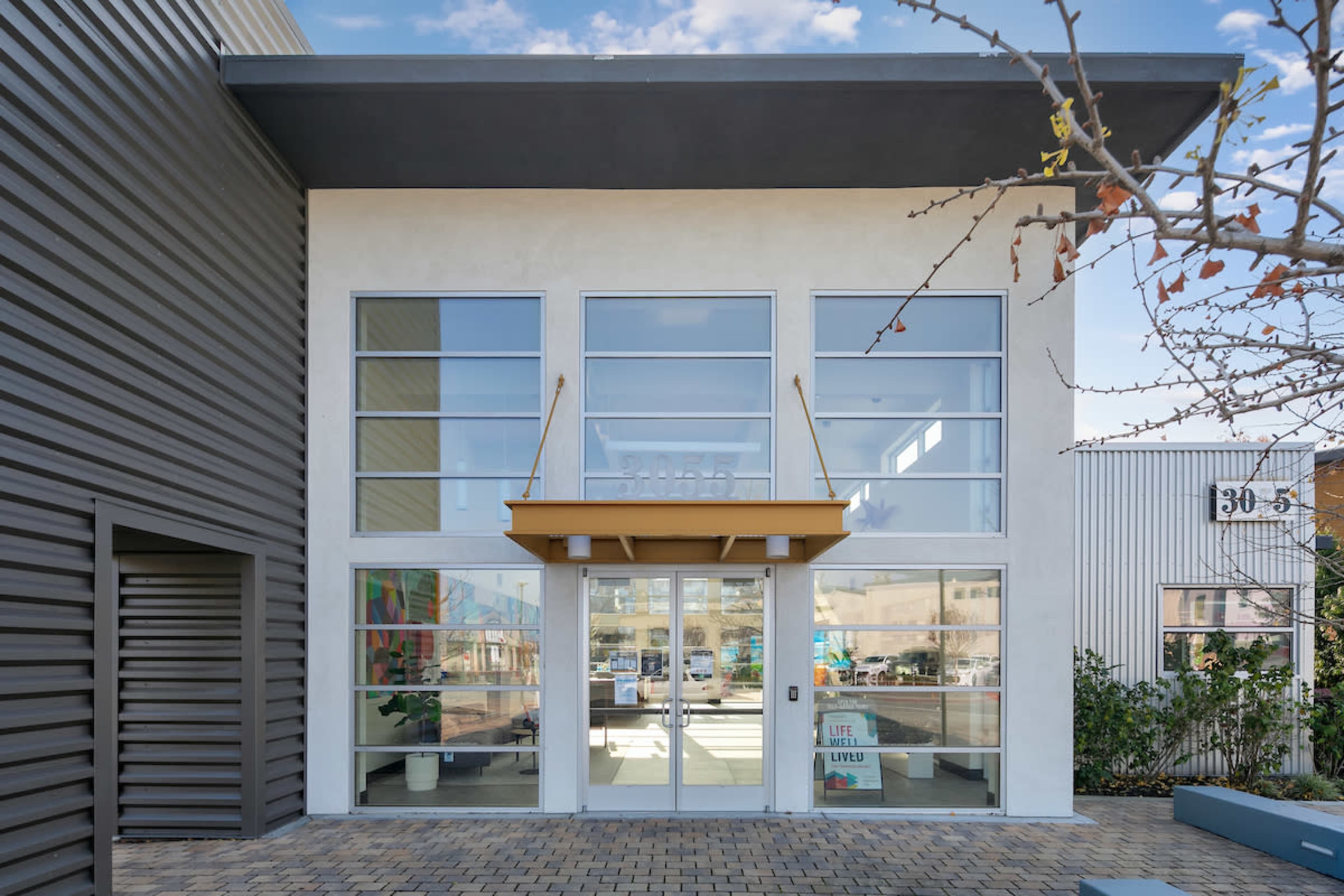 The image shows a modern commercial building with large glass doors and windows, framed by clean lines and a minimalist facade.