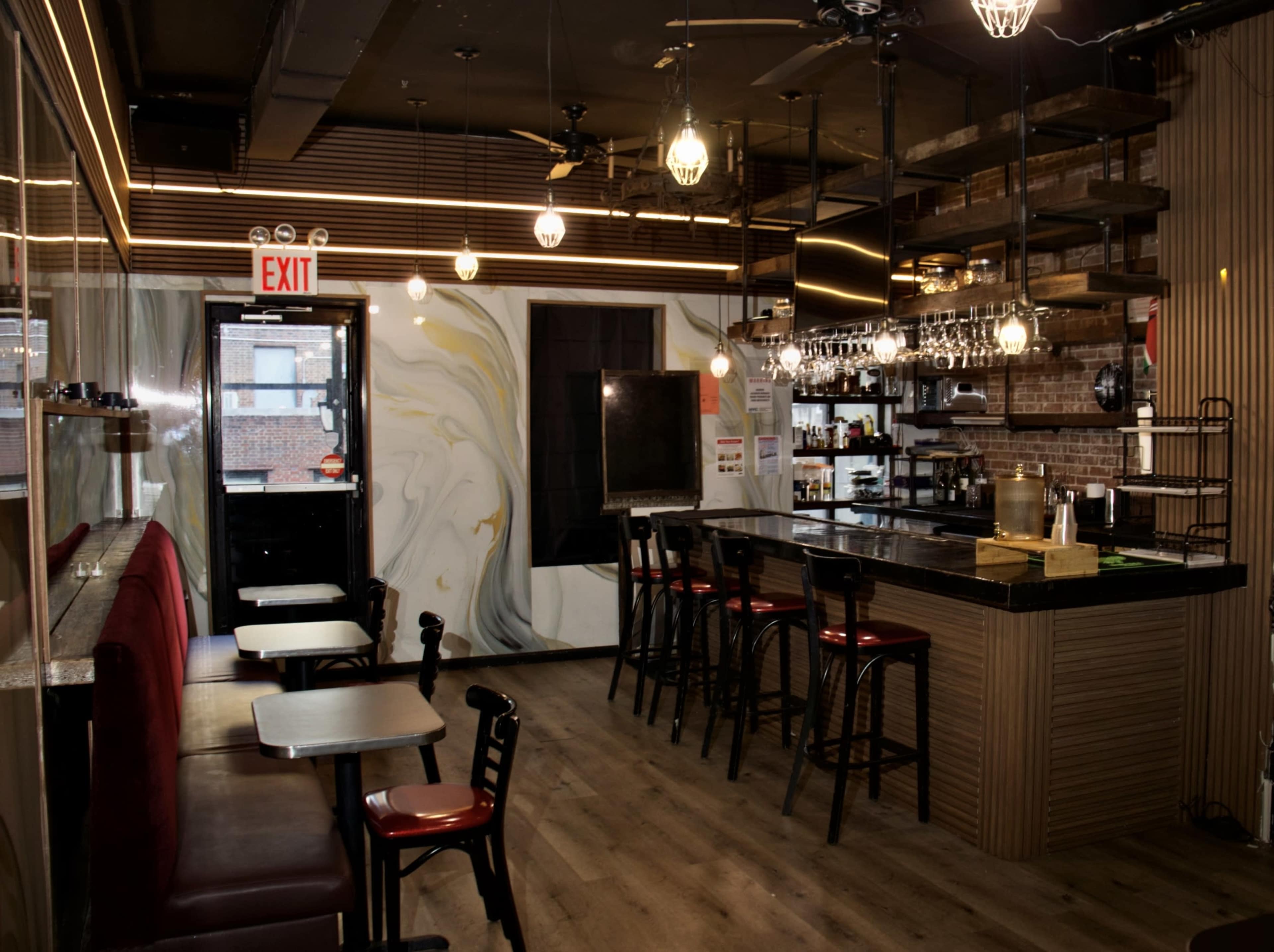 The image shows a modern restaurant interior featuring a bar area with hanging lights, wooden shelves, and red-accented seating.