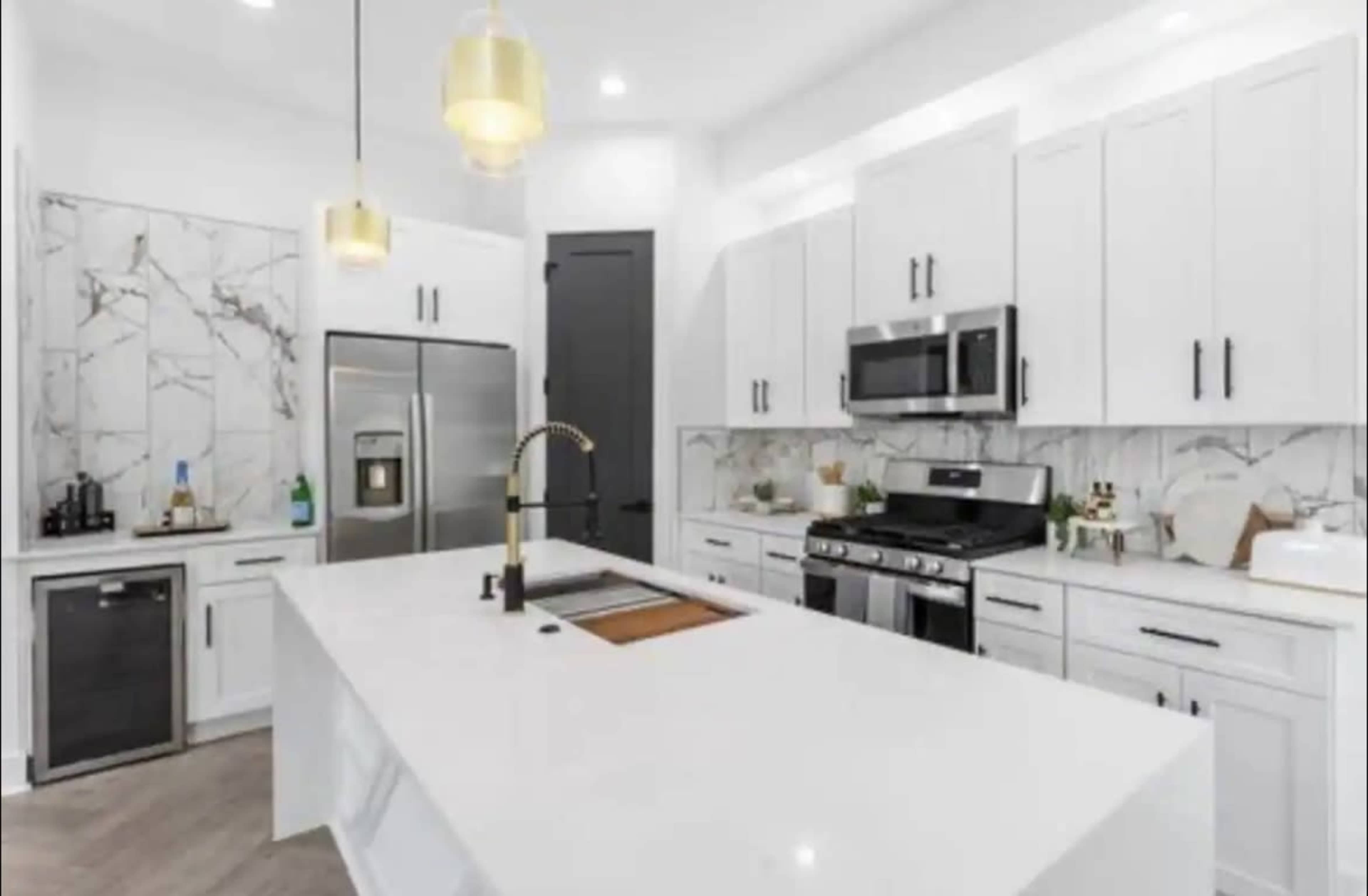 A modern kitchen featuring white cabinets, stainless steel appliances, and a marble backsplash.