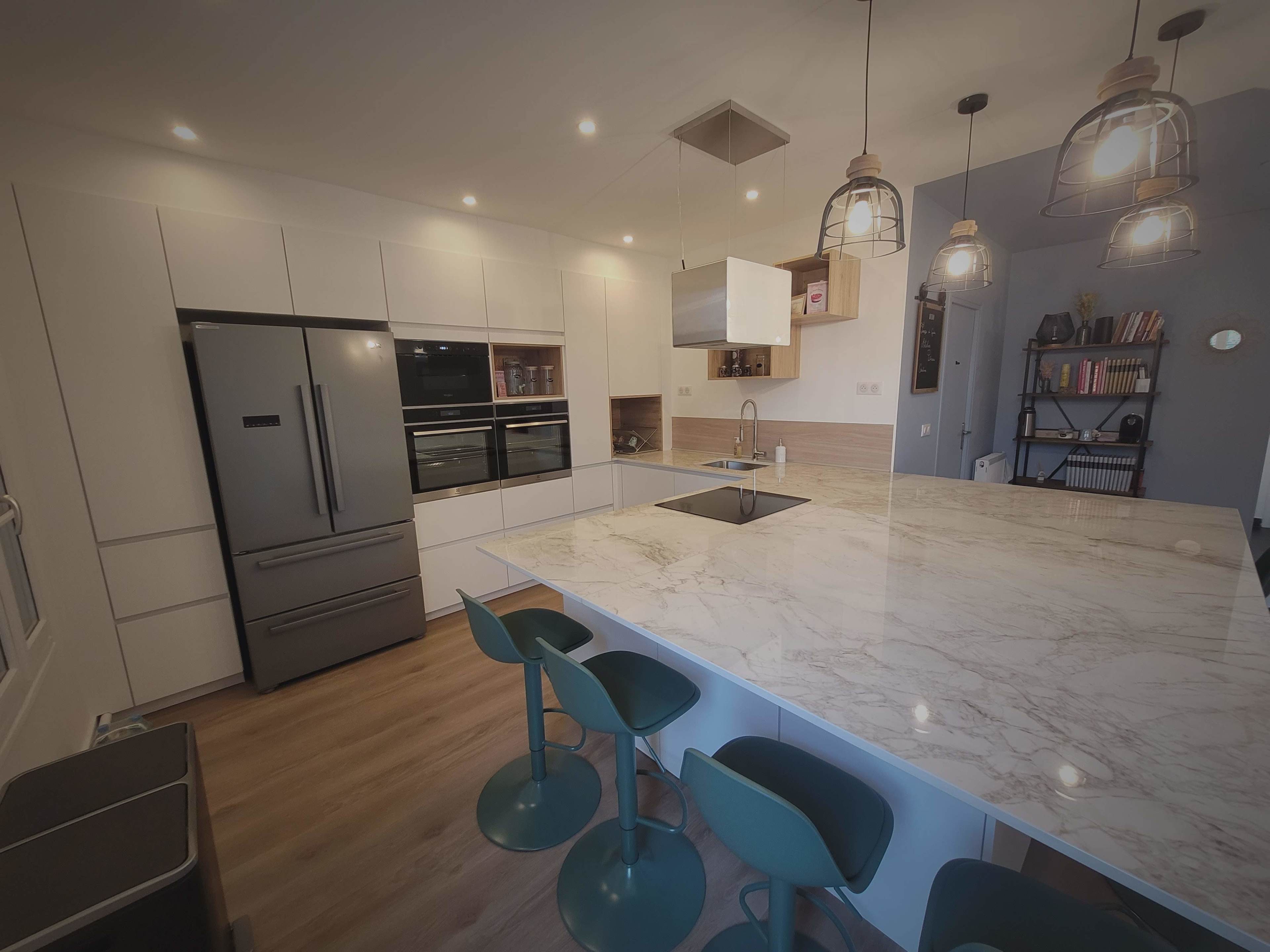 A modern kitchen with a large marble island, sleek cabinetry, stainless steel appliances, and pendant lighting above the island.