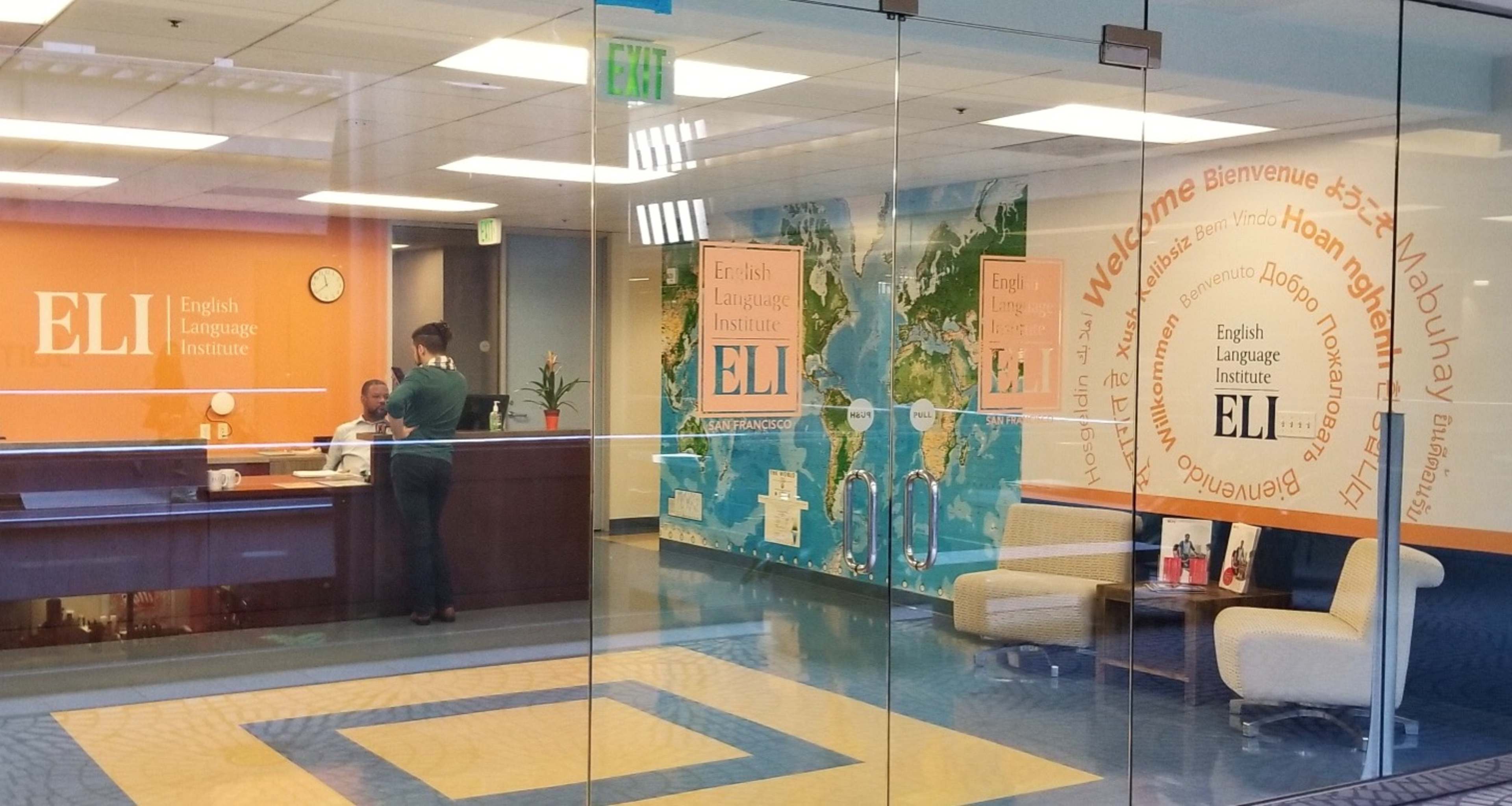 The reception area of the English Language Institute, featuring a front desk, a map mural, and multilingual welcome messages on the walls.