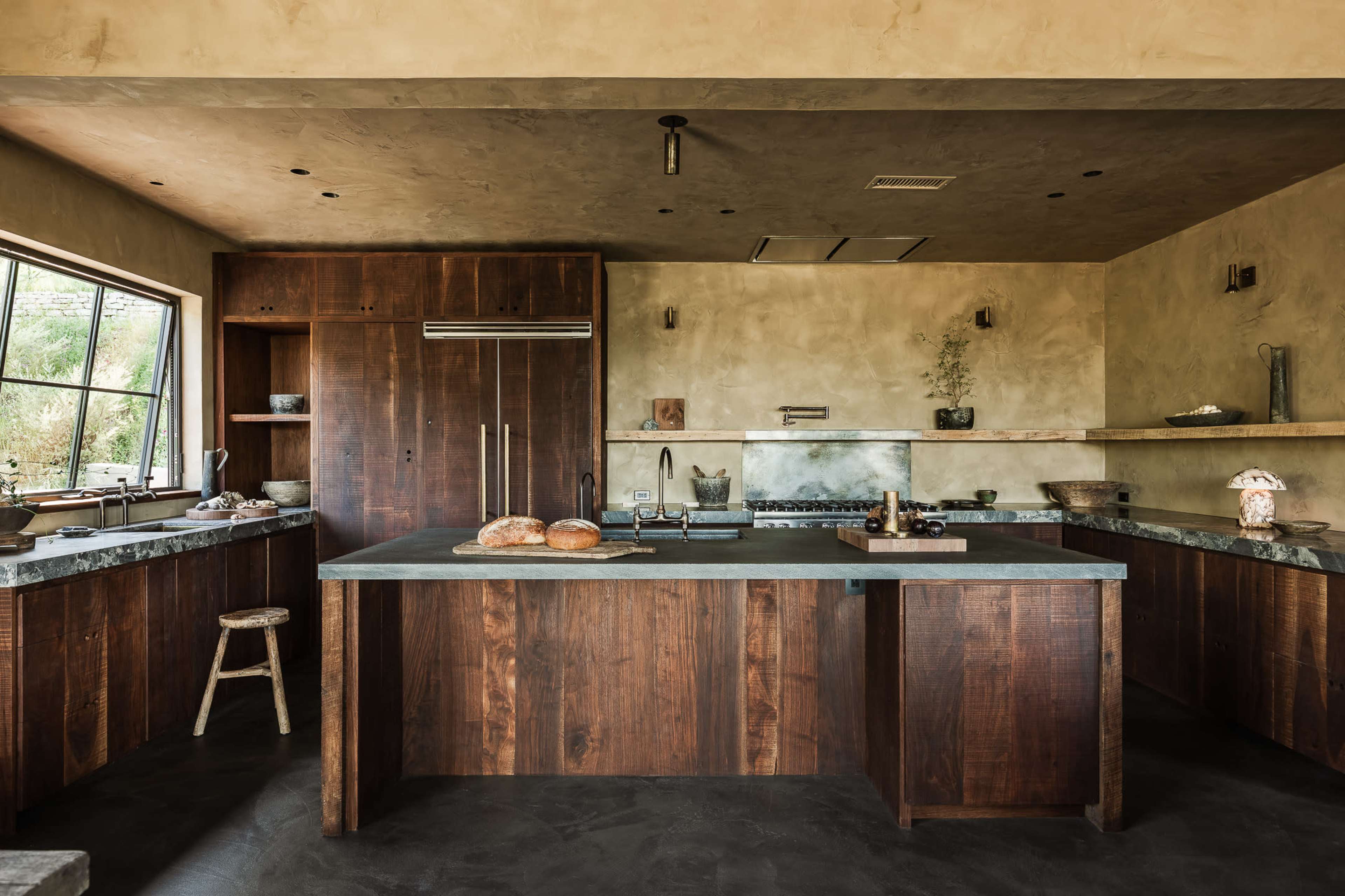 The kitchen features wooden cabinetry, a large stone countertop, and minimalist decor, situated within a spacious, modern layout.