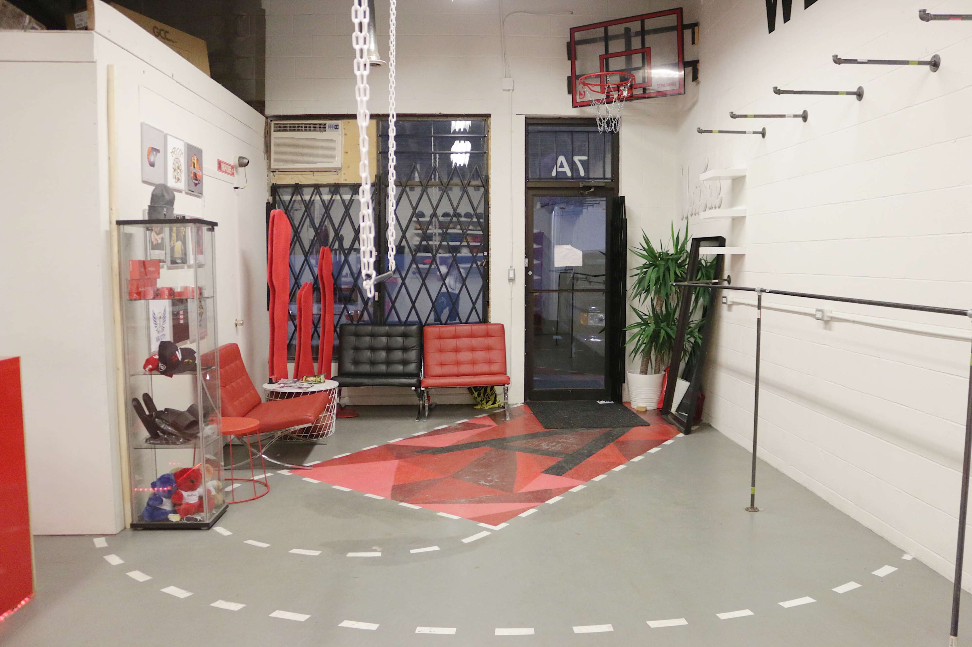 A modern, minimalist room featuring red and white decor, seating areas, exercise equipment, and a basketball hoop.