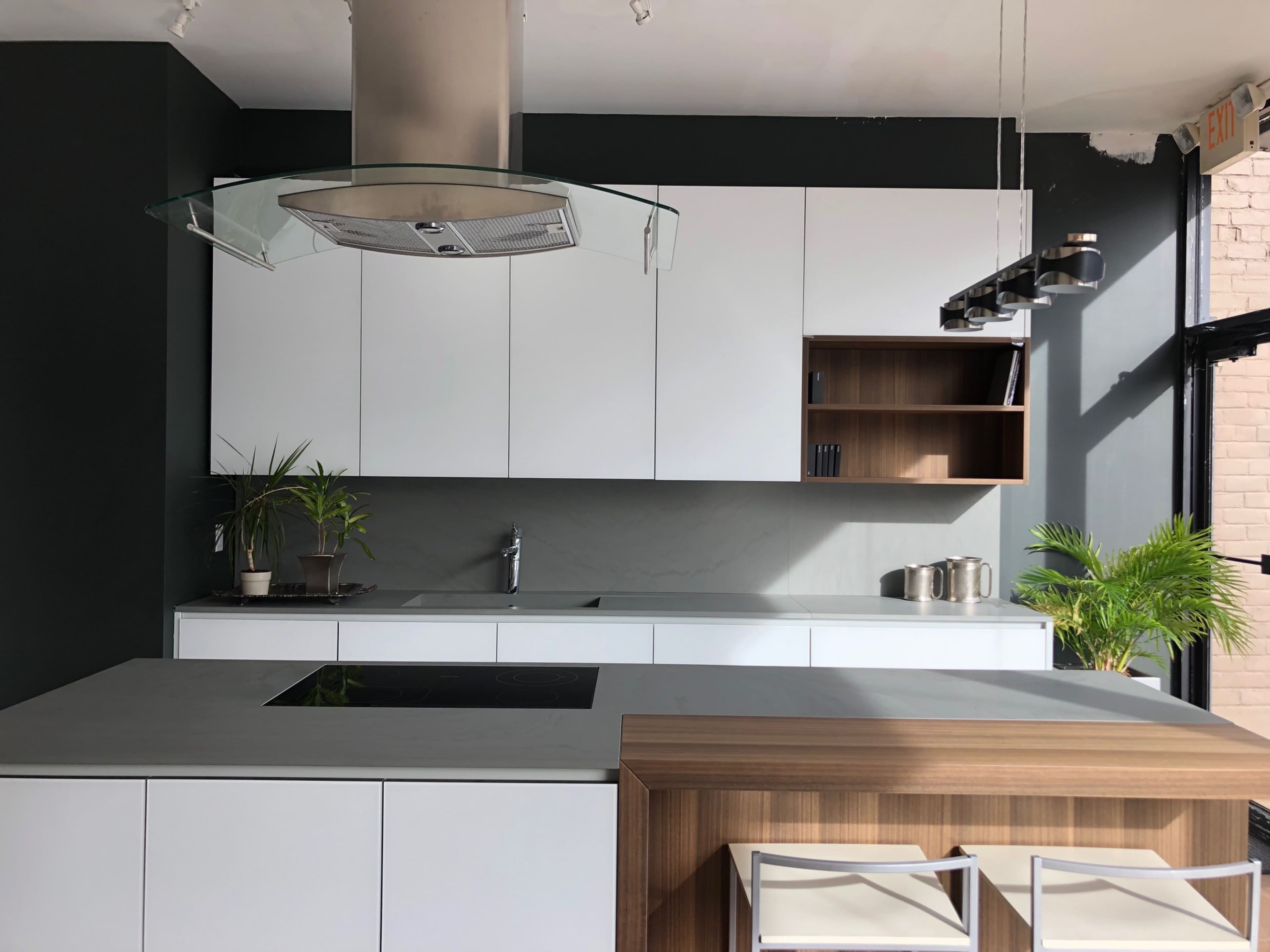 A modern kitchen features sleek white cabinetry, a gray countertop, and a kitchen island with a wooden accent.