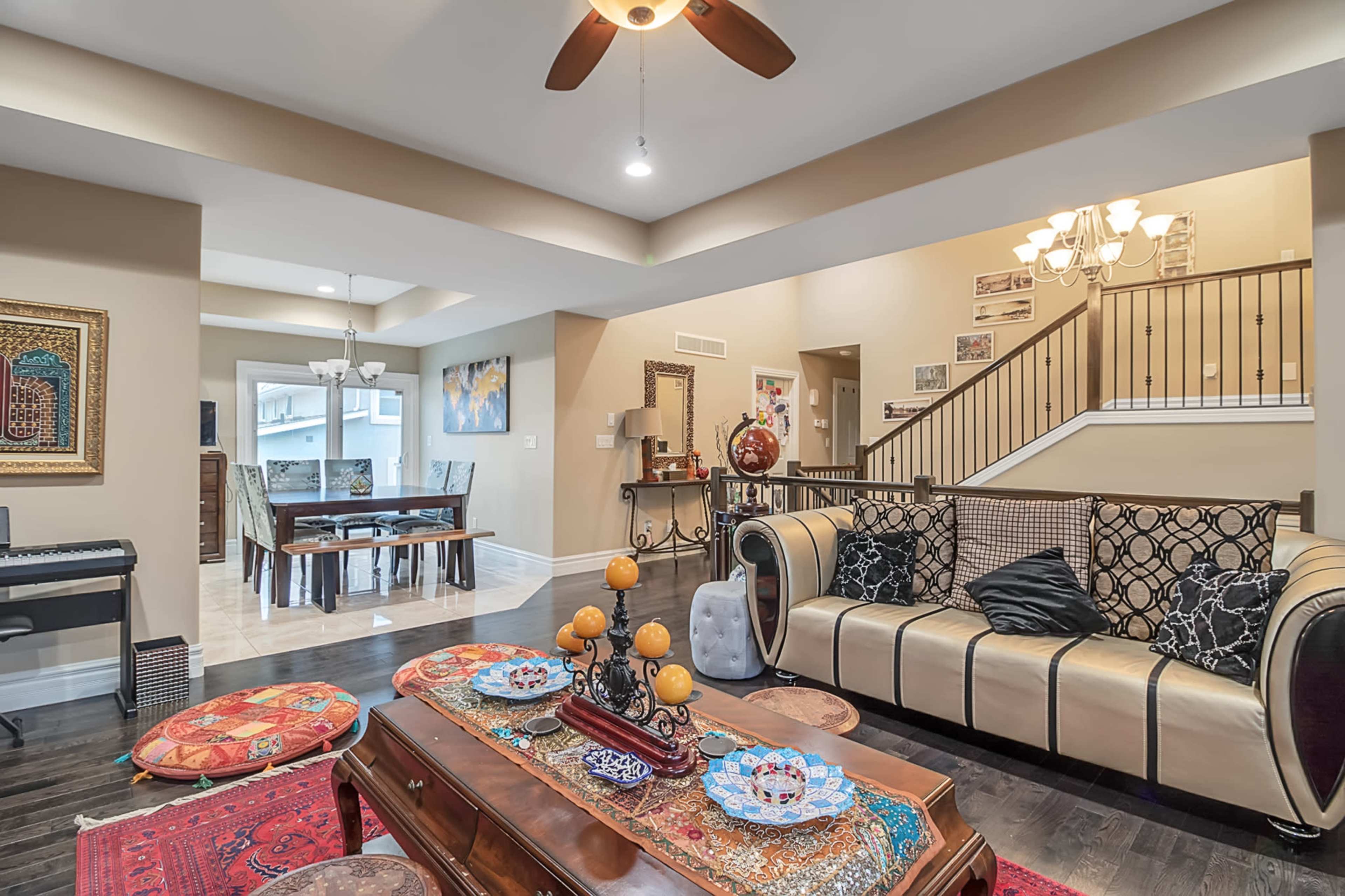 A spacious living room with a patterned sofa, a coffee table adorned with decorative items, and dining space visible in the background.