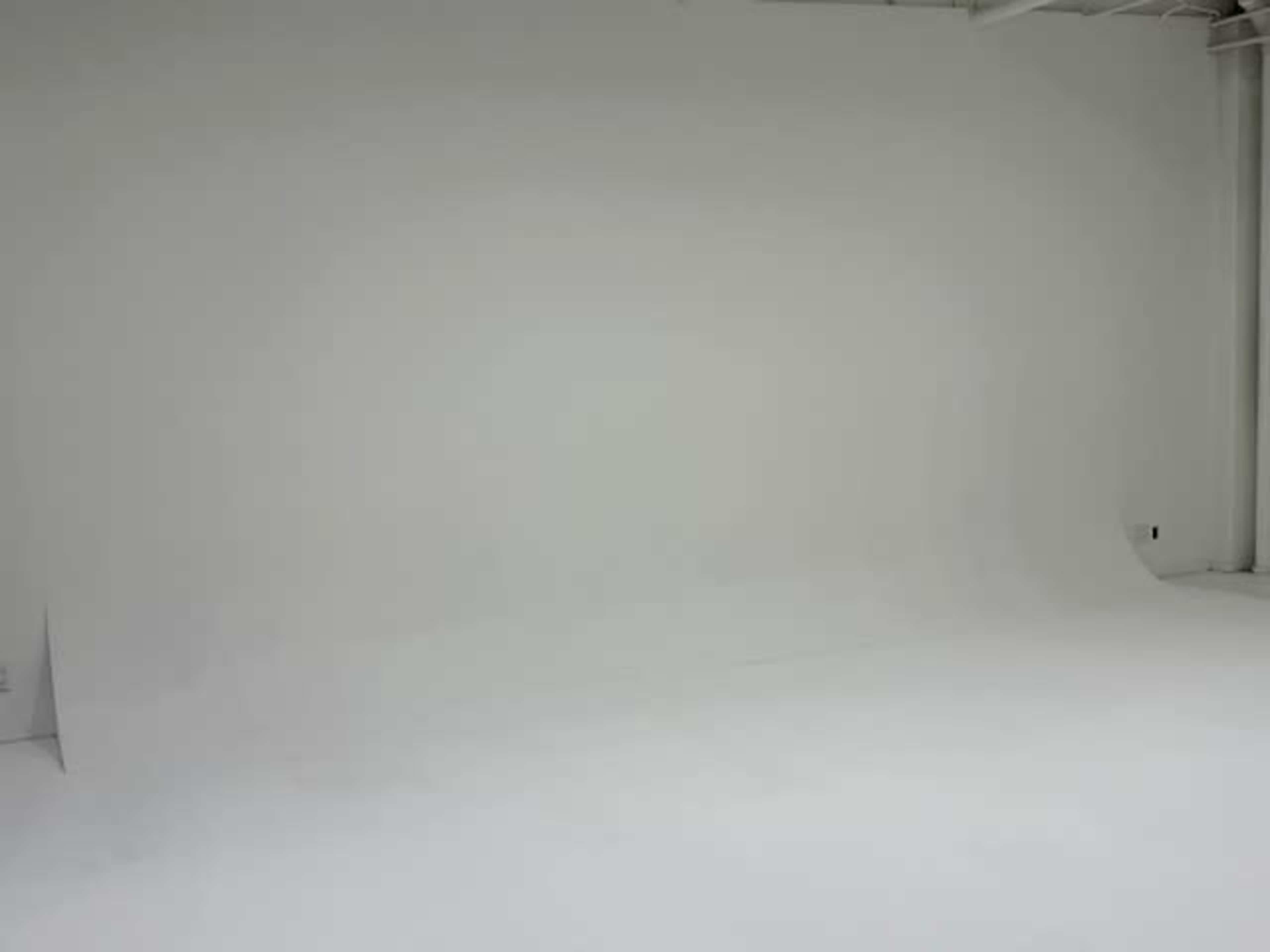 A blank, white studio space features a seamless background and a smooth floor.