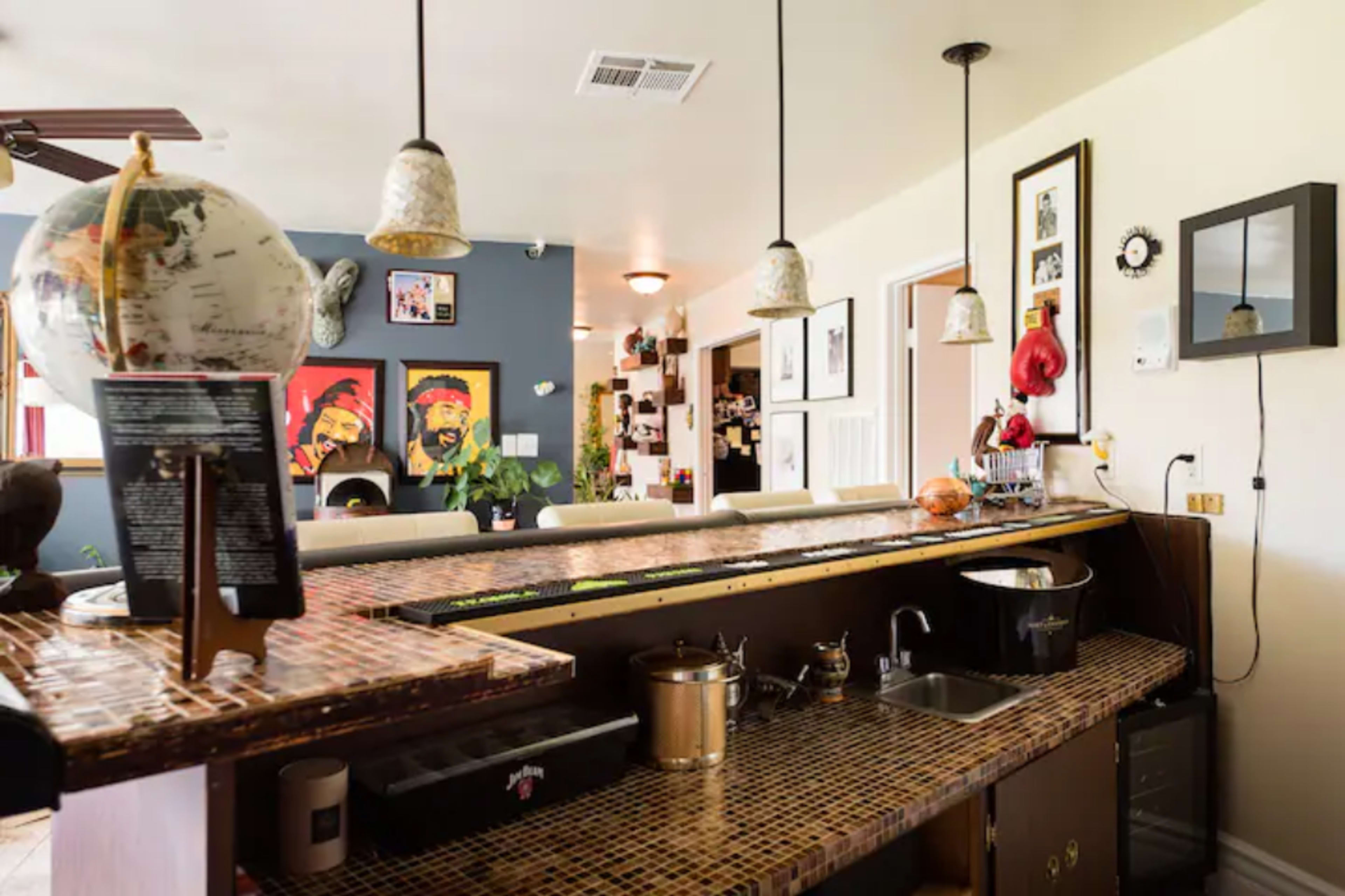 A kitchen bar area with a mosaic countertop, overhead pendant lights, and various decorative items on the wall.