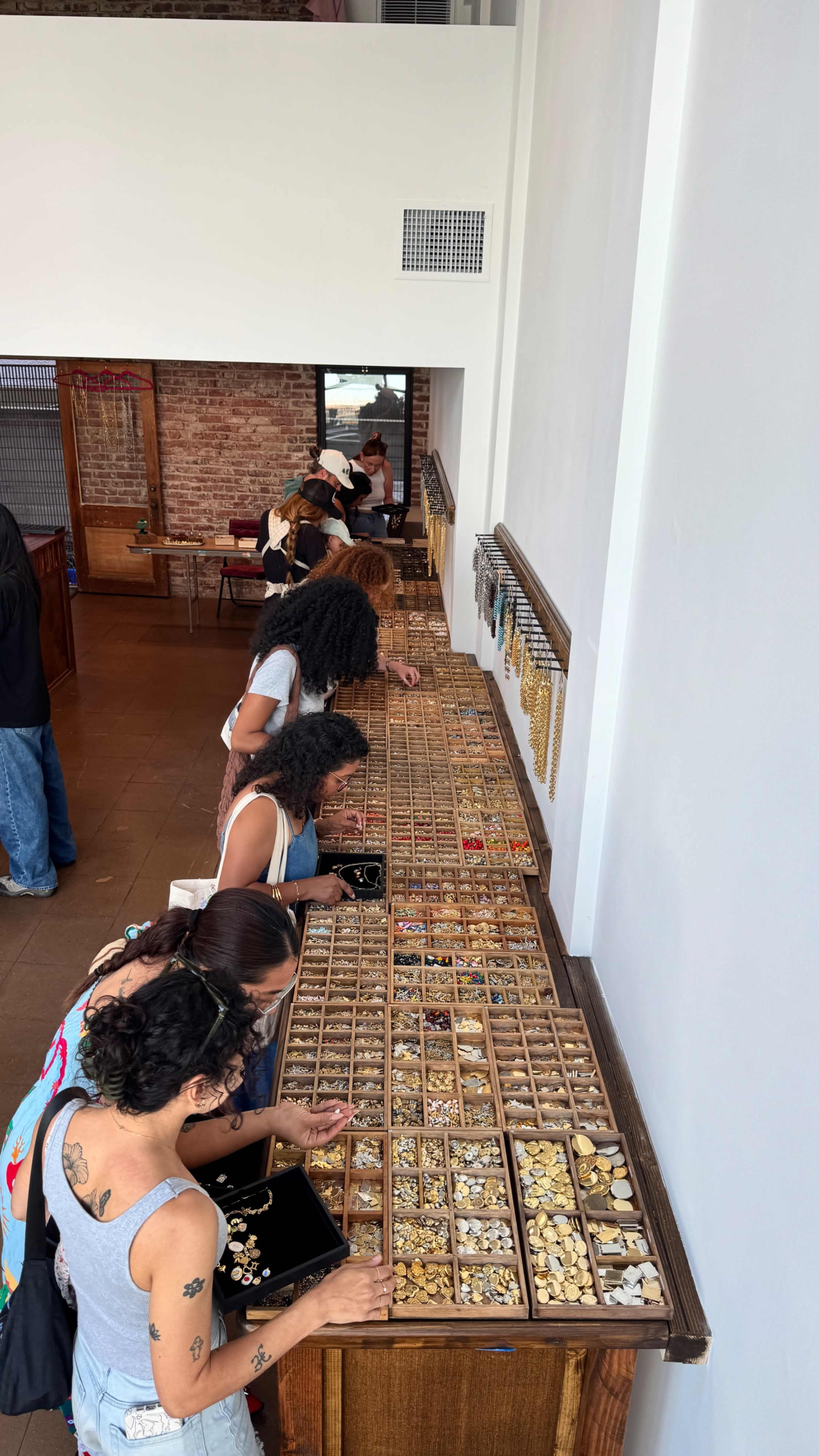 A group of people is browsing through rows of organized jewelry items displayed in trays at a shop.