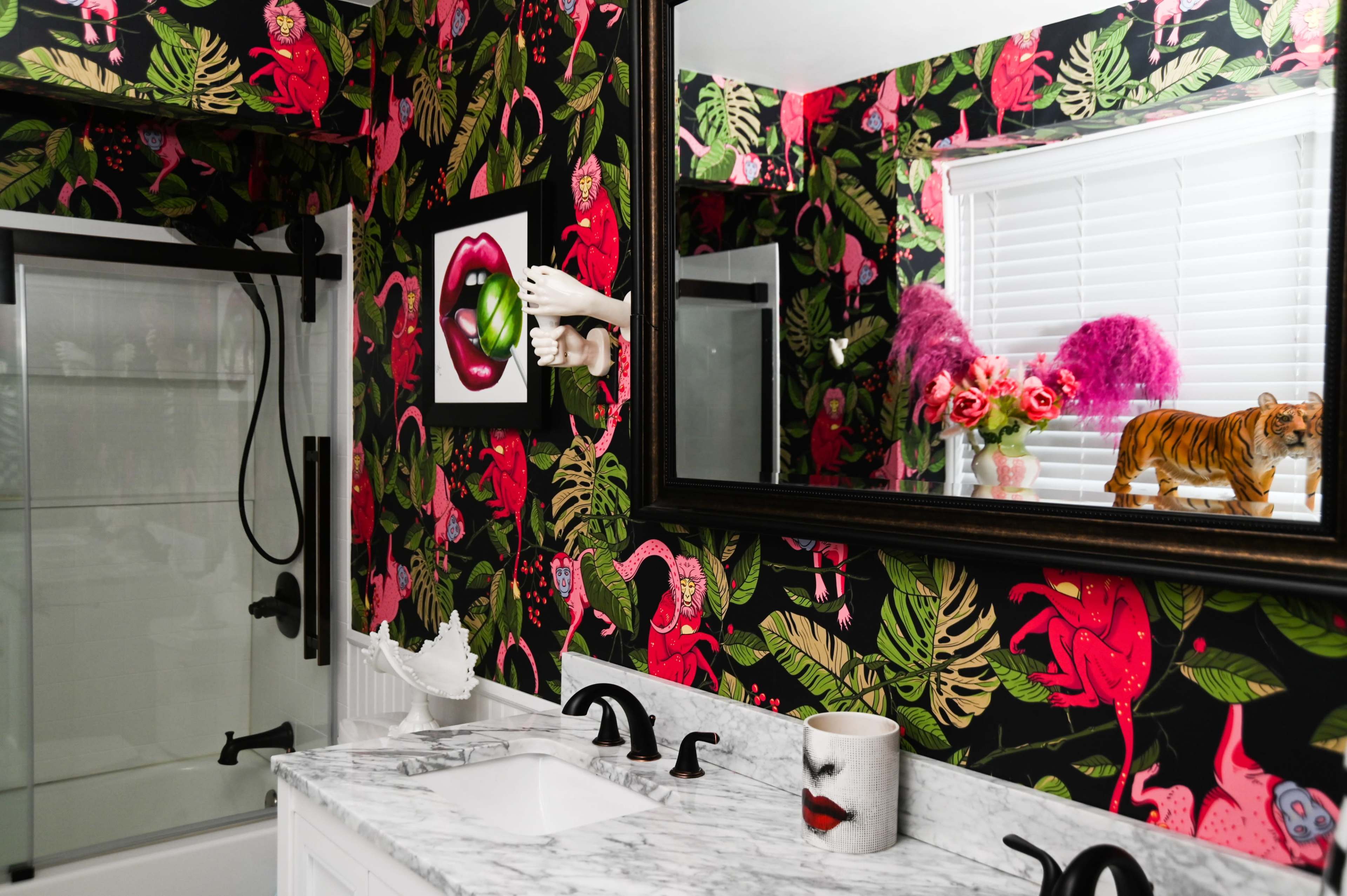 The bathroom features bold floral wallpaper, a marble countertop with decorative items, and a large mirror reflecting the vibrant decor.