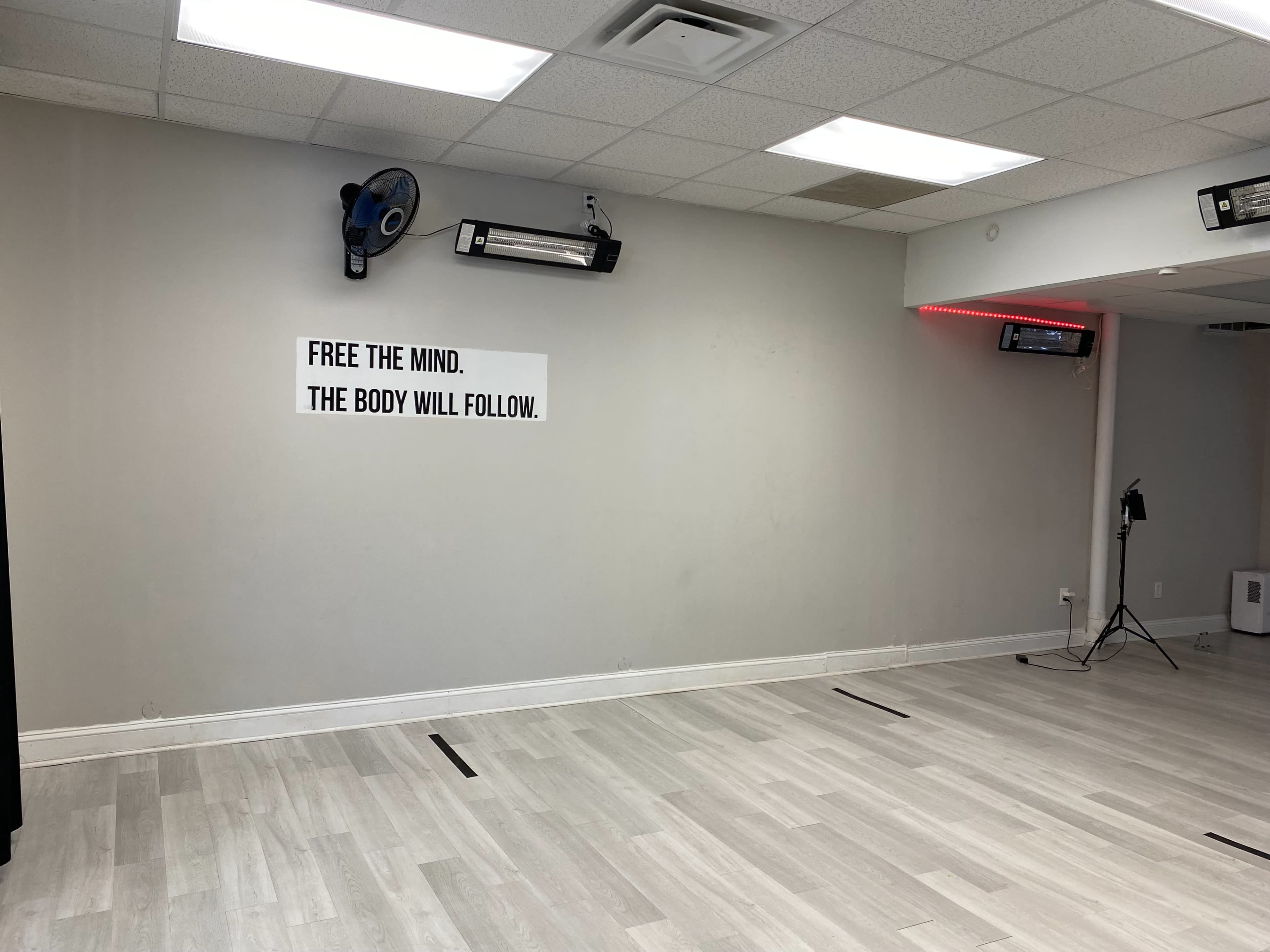 A spacious, empty room with a gray wall displaying the phrase "FREE THE MIND. THE BODY WILL FOLLOW."