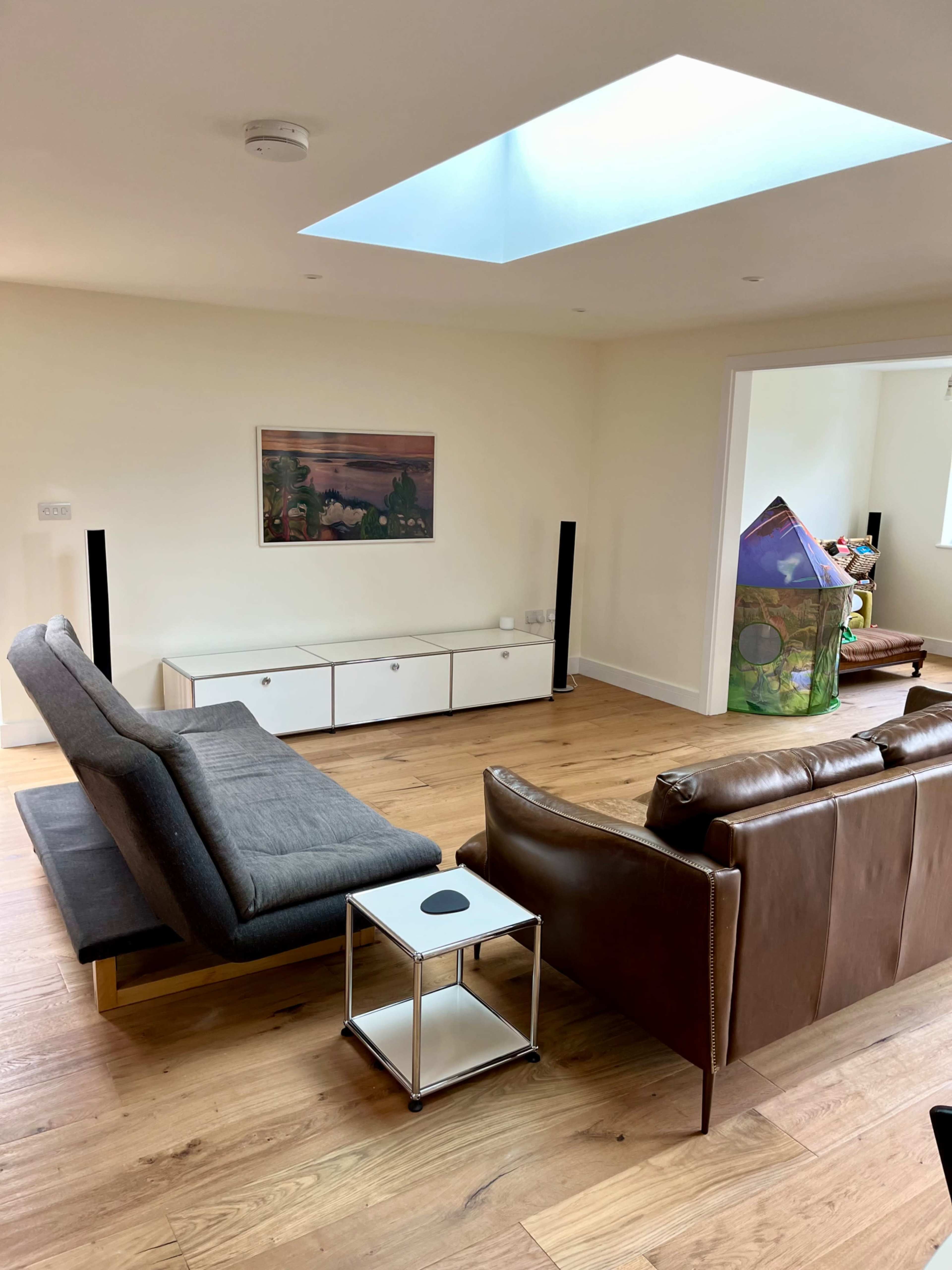 A spacious living room with two sofas, a small coffee table, a low cabinet, and a skylight above.
