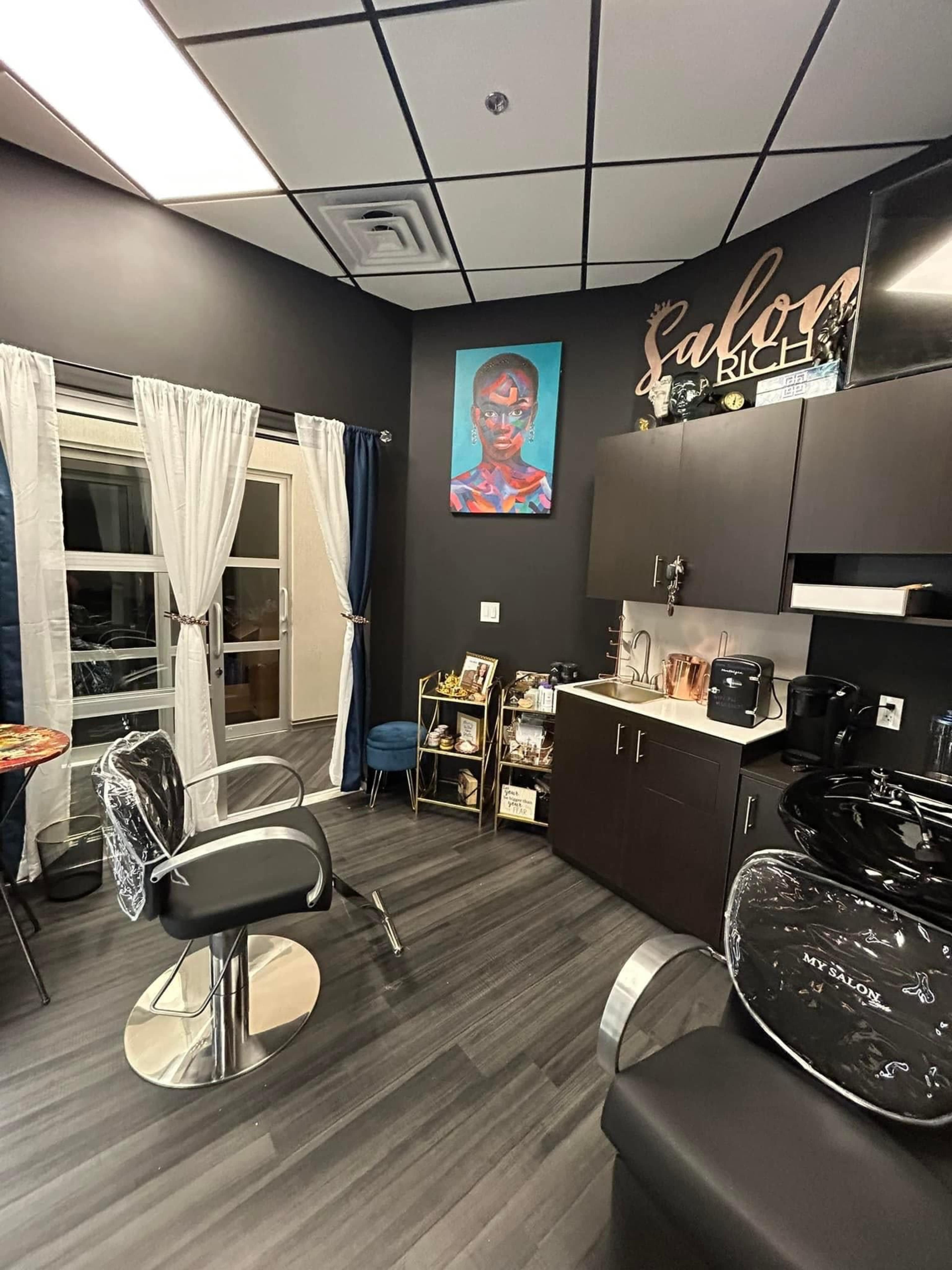 The image shows a modern salon interior featuring a styling chair, a washing station, and a colorful artwork on the wall, with curtains framing a window.
