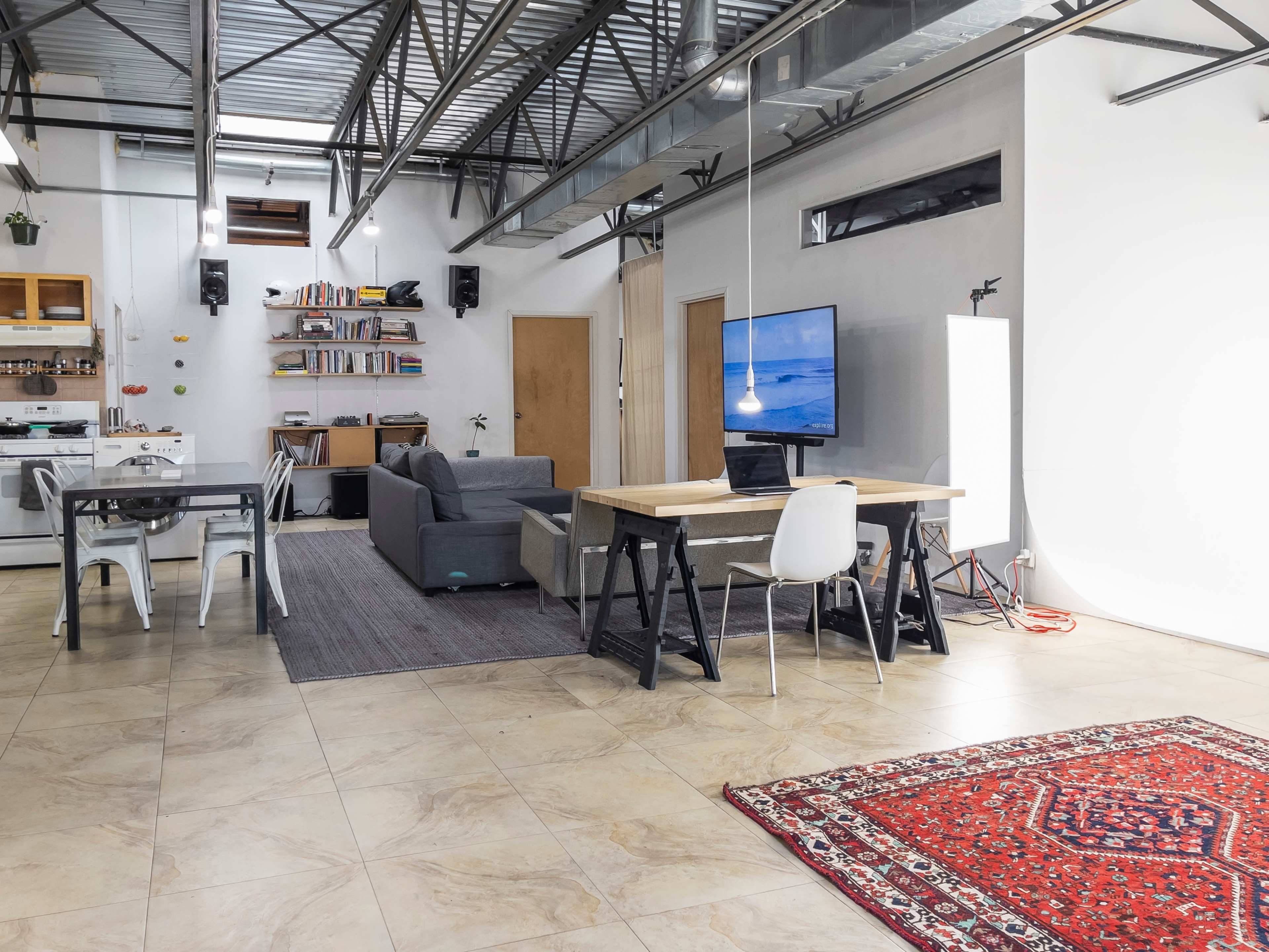 An open-concept living space featuring a dining area with a table and chairs, a sofa, a television, and bookshelves along one wall.