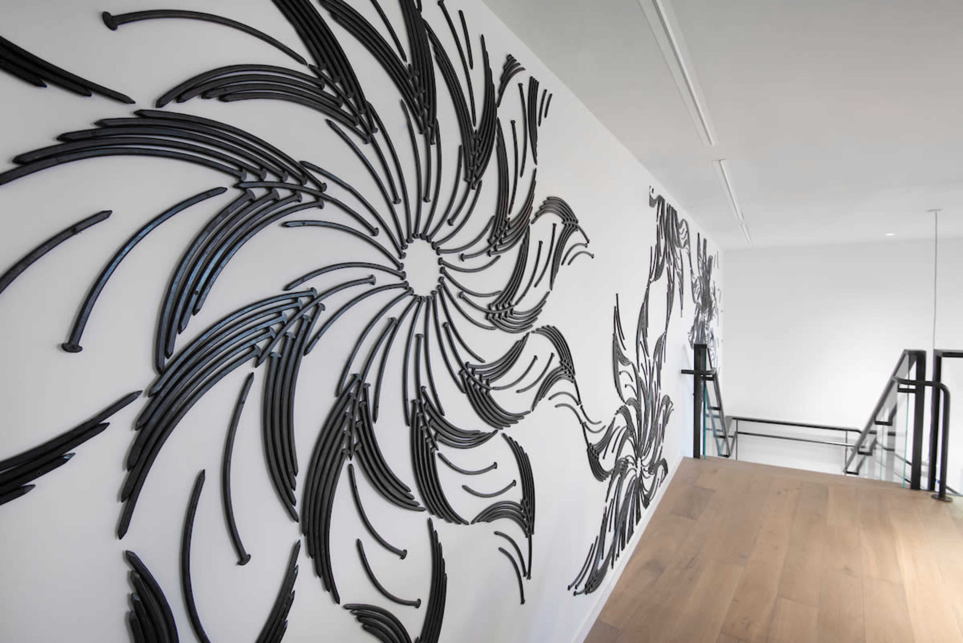 A modern interior hallway featuring an artistic wall installation of swirling black designs made from curved, linear materials.