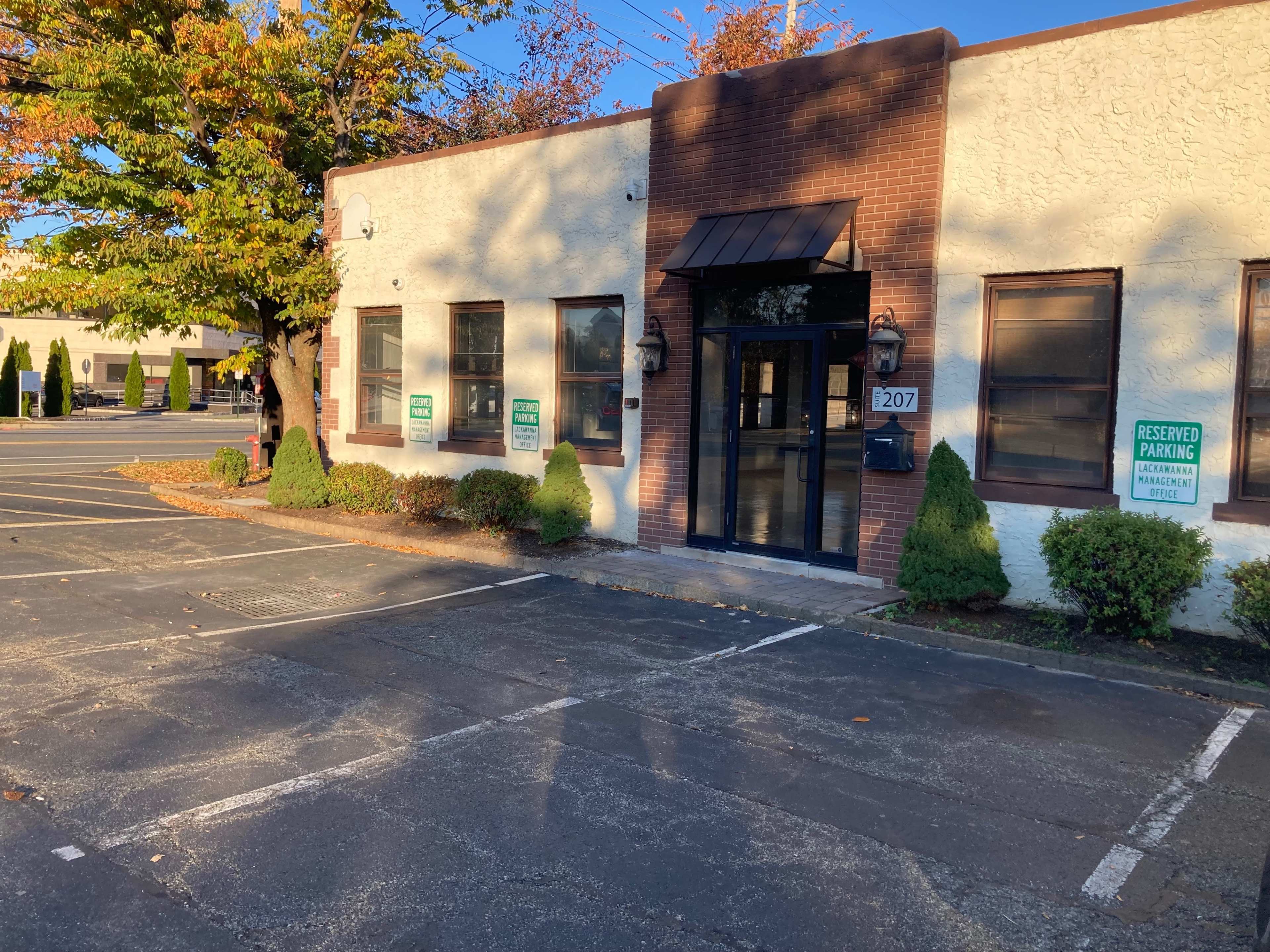 A single-story commercial building with a brick and stucco facade, located beside a parking lot with reserved parking signs.
