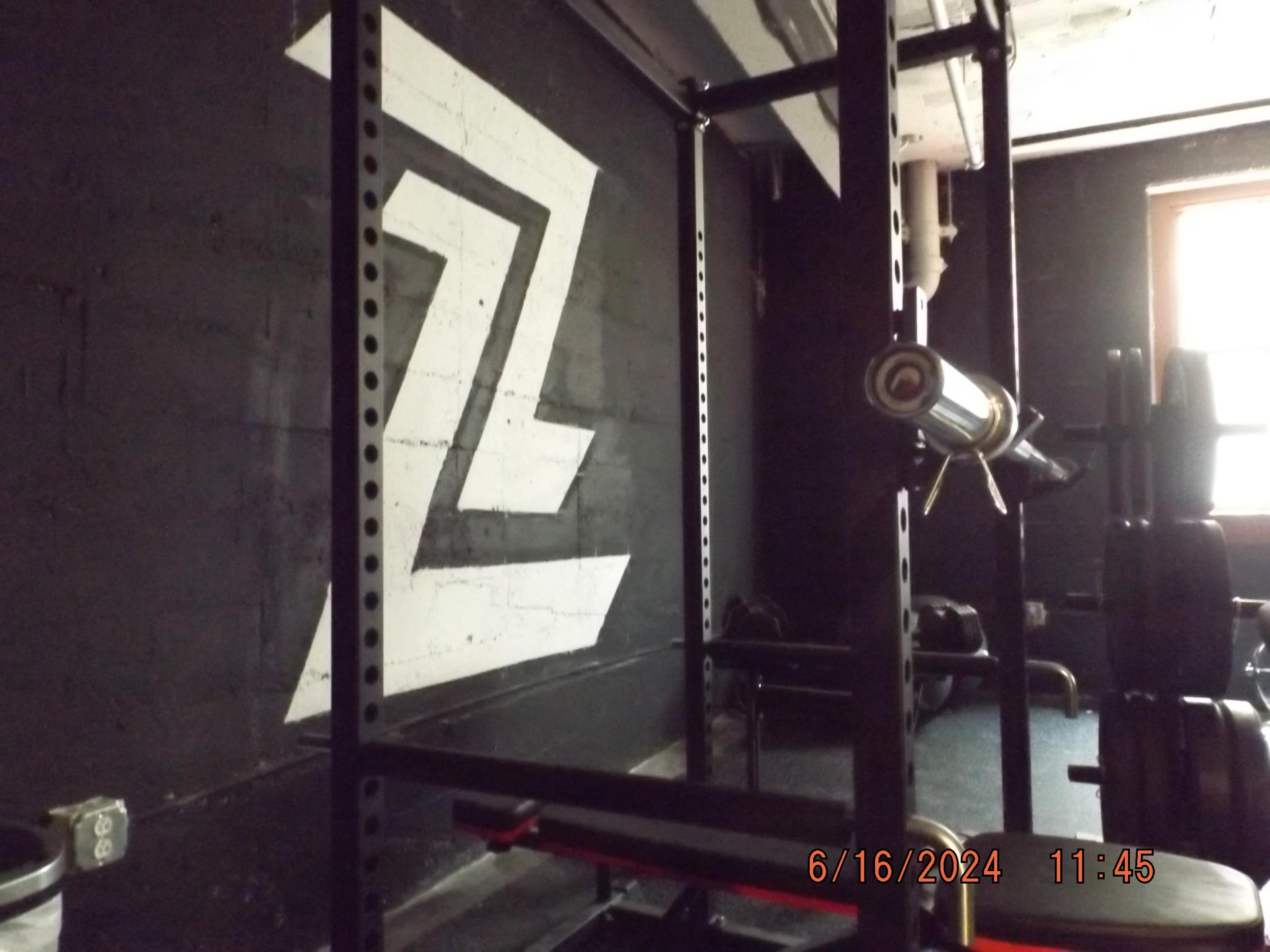 The image shows a gym interior featuring a power rack and a wall painted with a large "Z" logo.