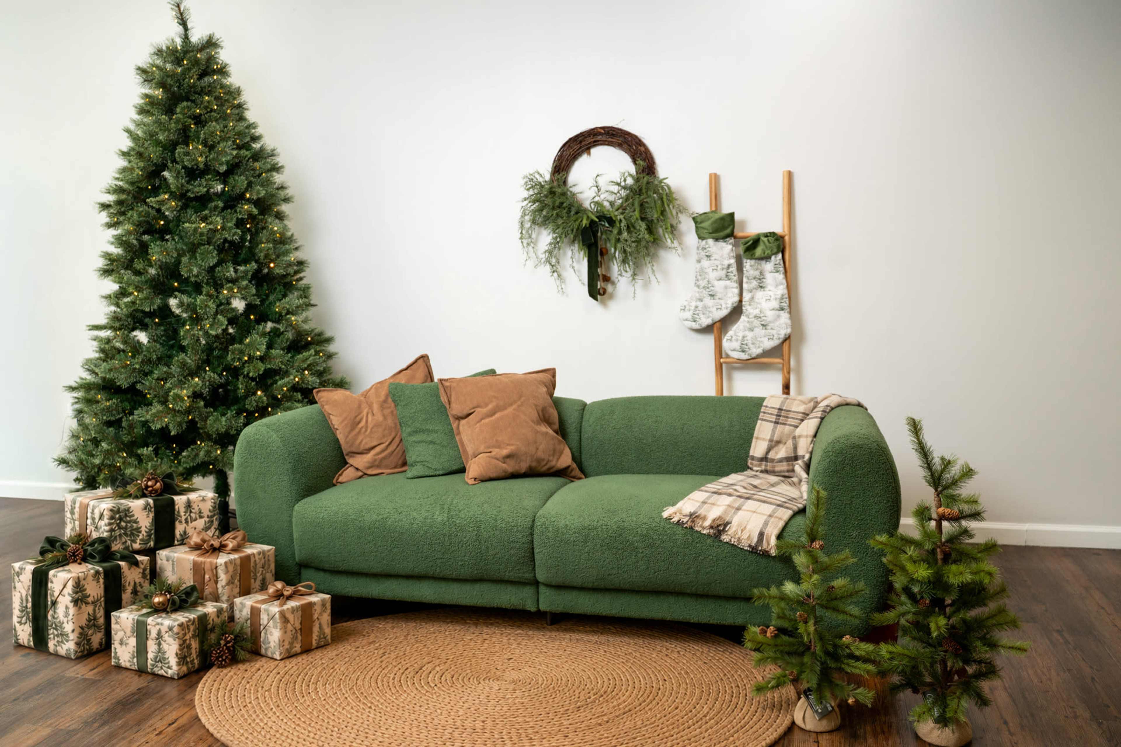 A green sofa is positioned in a cozy room decorated with a Christmas tree, holiday stockings, and neatly wrapped presents.