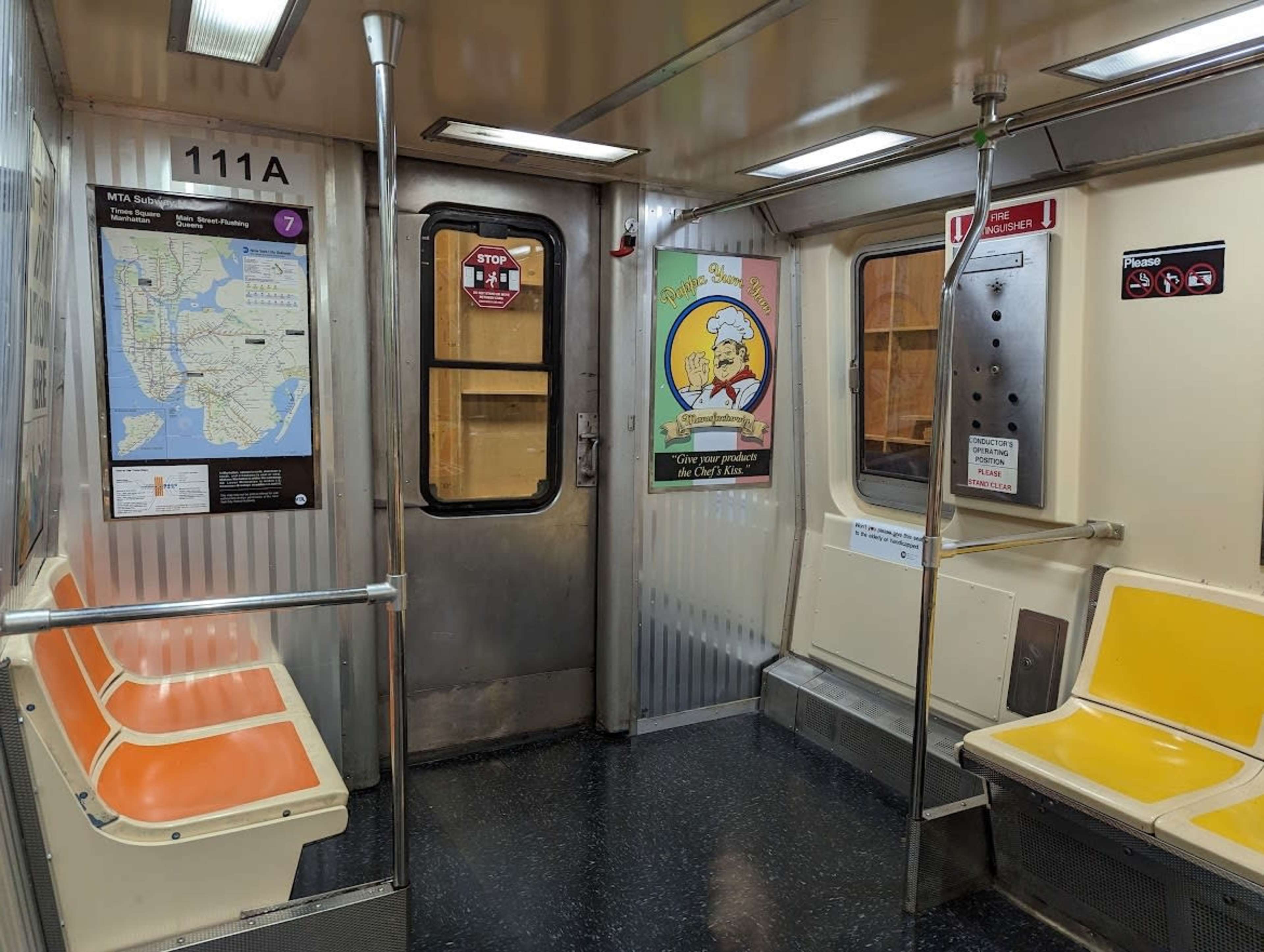 The image shows the interior of a subway train car with orange and yellow seats, a map of the transit system on one wall, and a poster on another wall.