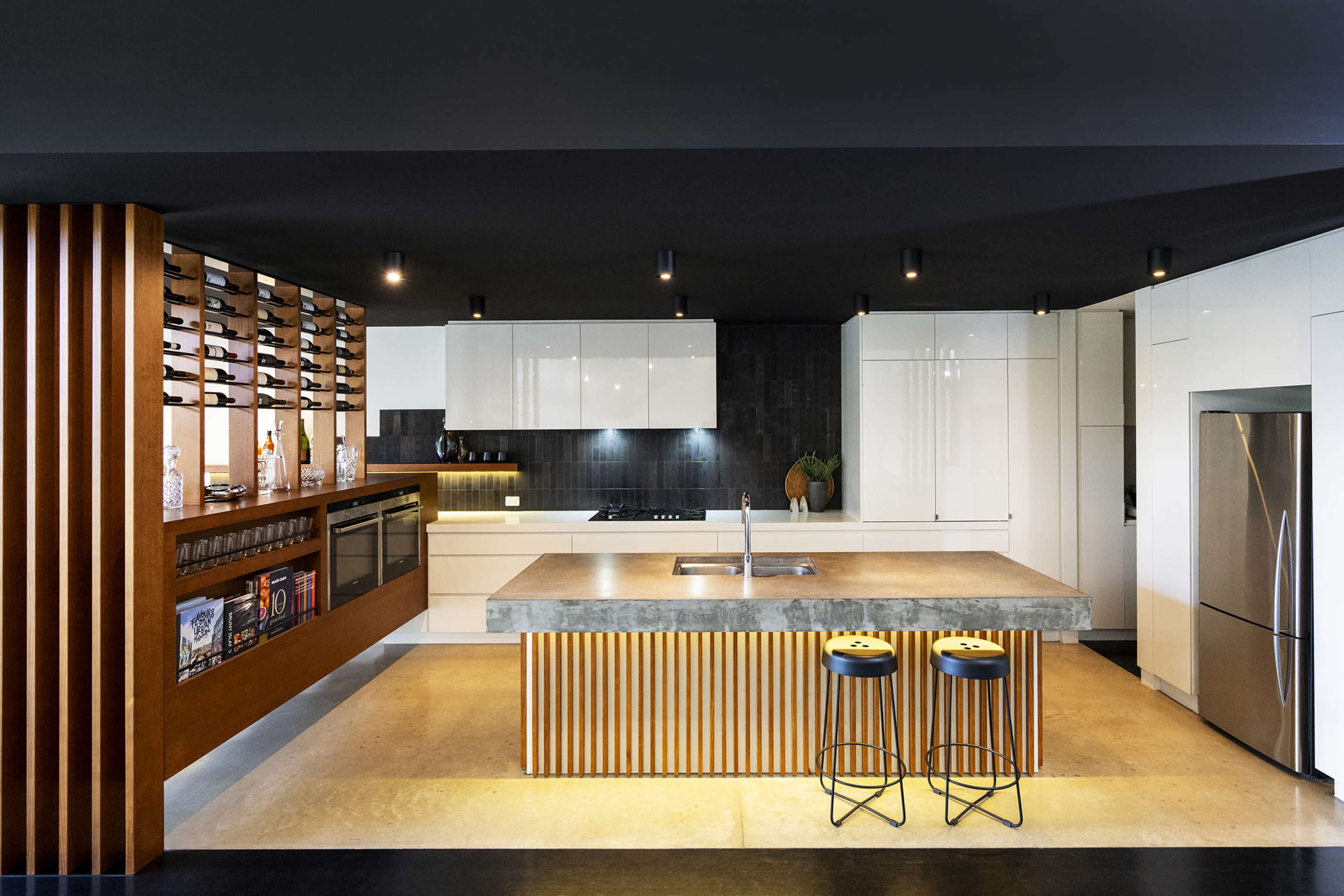 The kitchen features a modern design with a central island, sleek cabinetry, and a wine storage display.