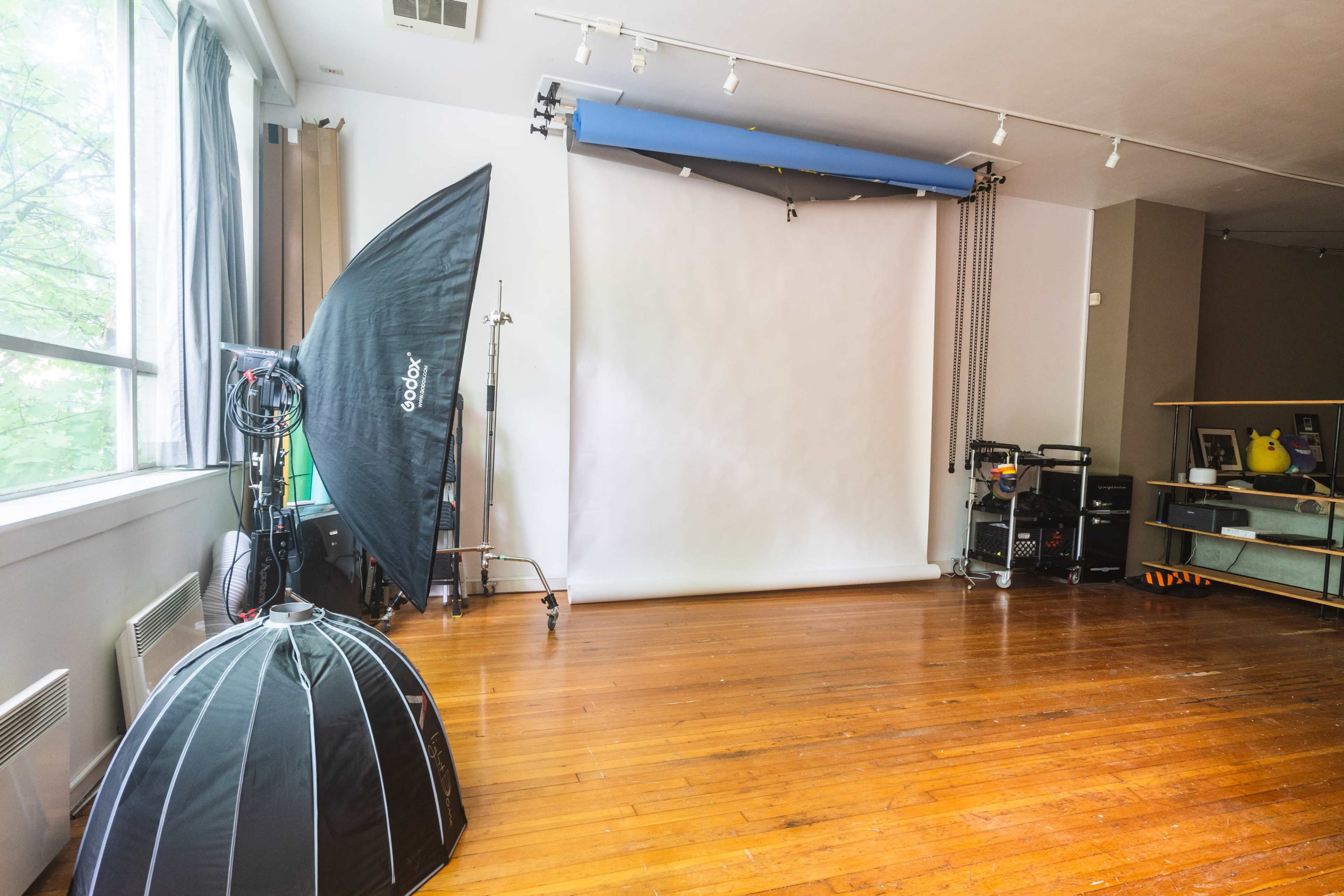 A photography studio with a large softbox, a blank backdrop, and wooden flooring.