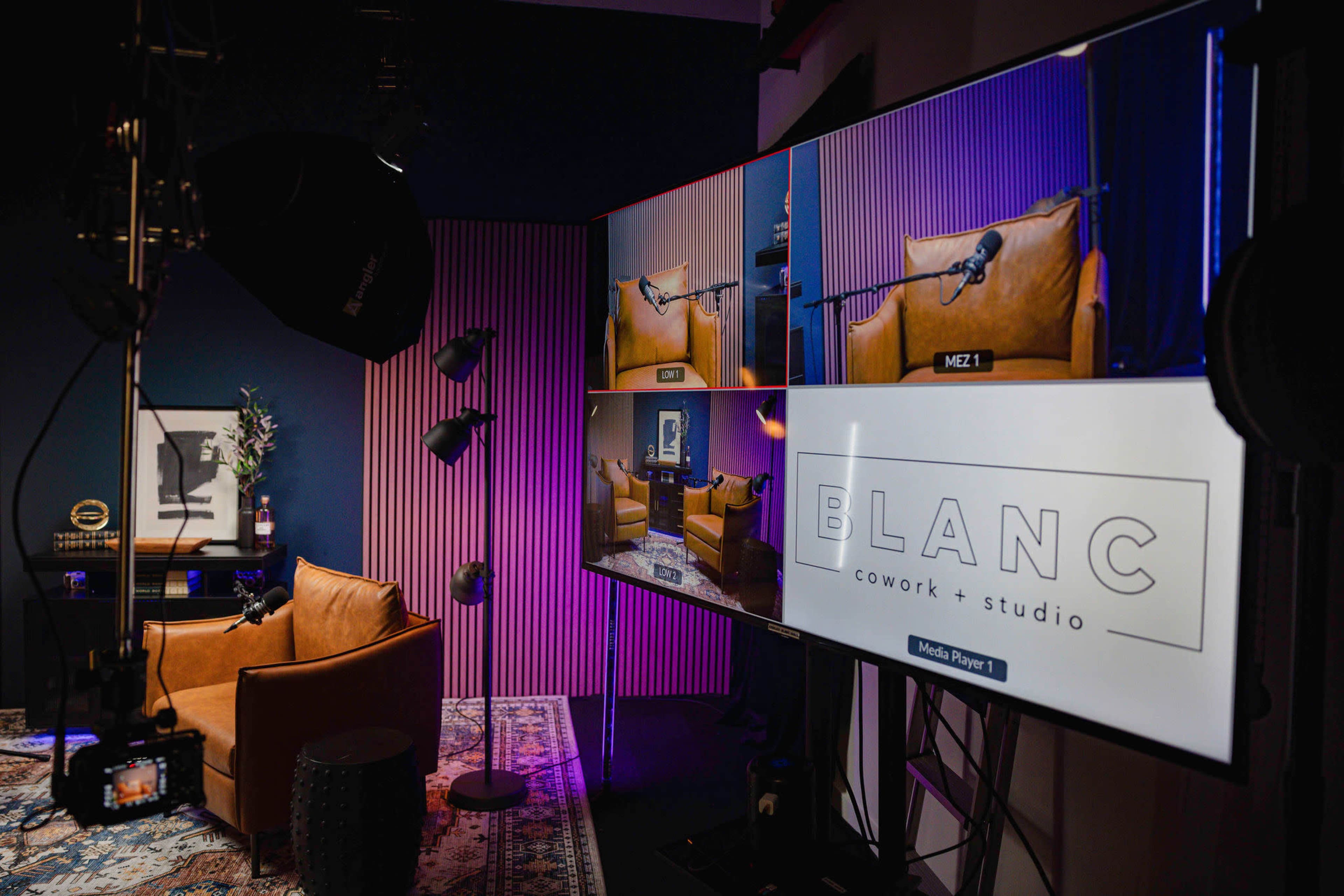 A modern studio setup features three screens displaying a cozy brown armchair with a microphone, surrounded by stylish lighting and décor.