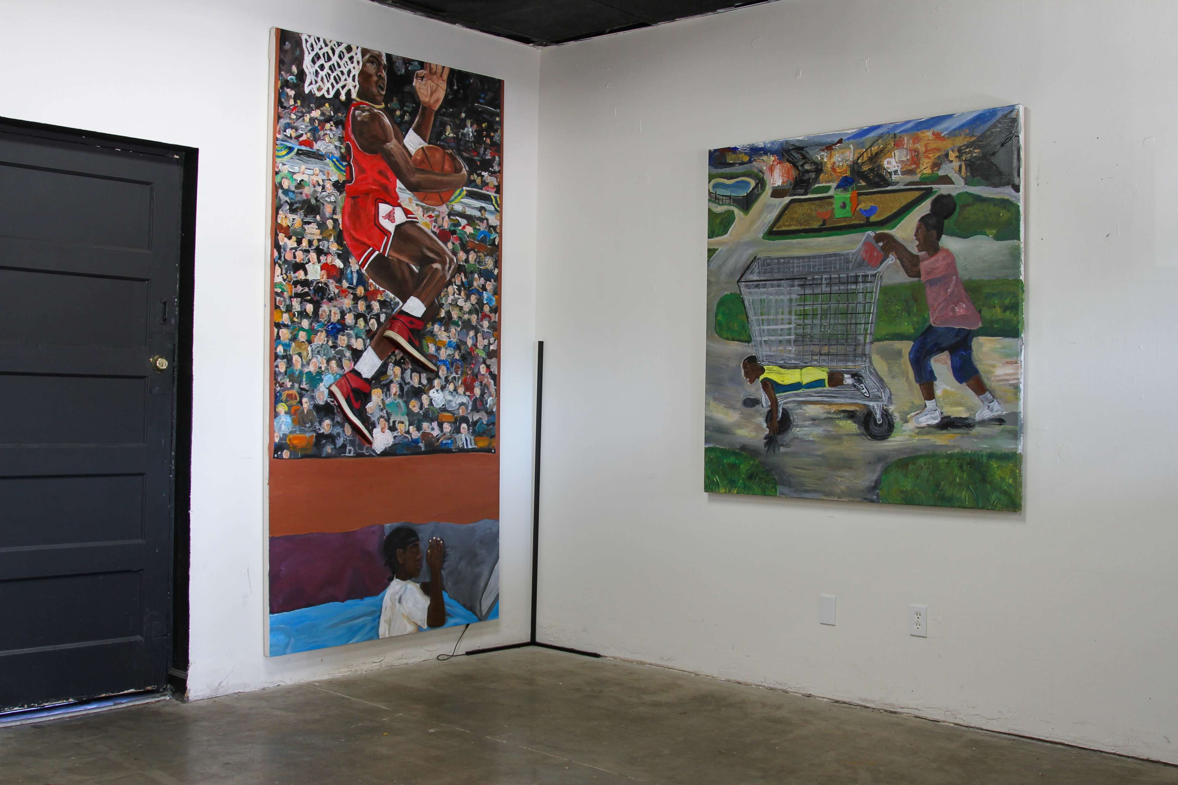 An interior space with two large paintings on the walls, one depicting a basketball player and the other showing a figure pushing a shopping cart.